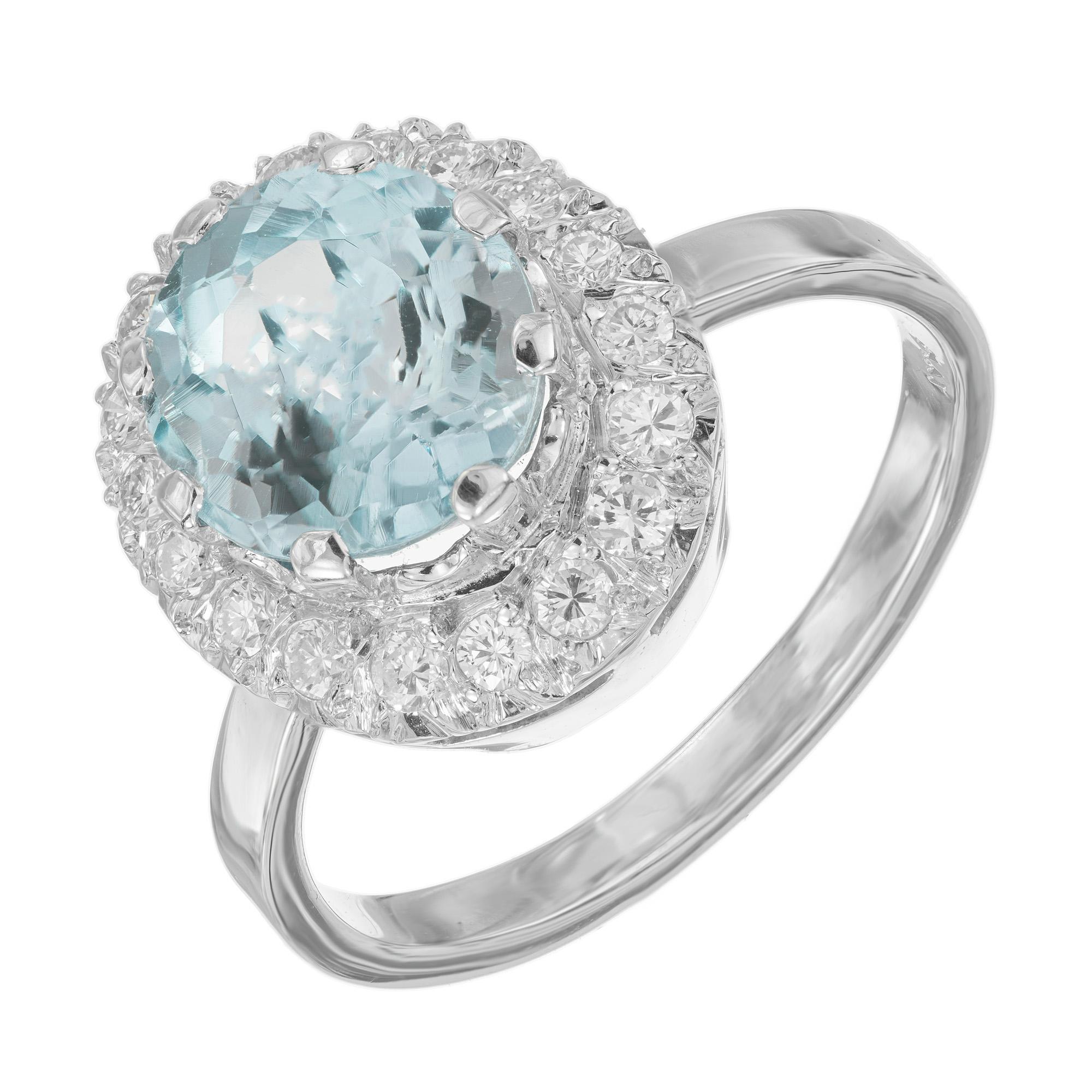 Vintage 1950's oval Aquamarine Diamond White Gold Halo Ring. The centerpiece of this ring features a mesmerizing 2.3 carat oval aquamarine, known for its captivating blue hue. Mounted in a platinum setting and encircled by a halo of 18 dazzling