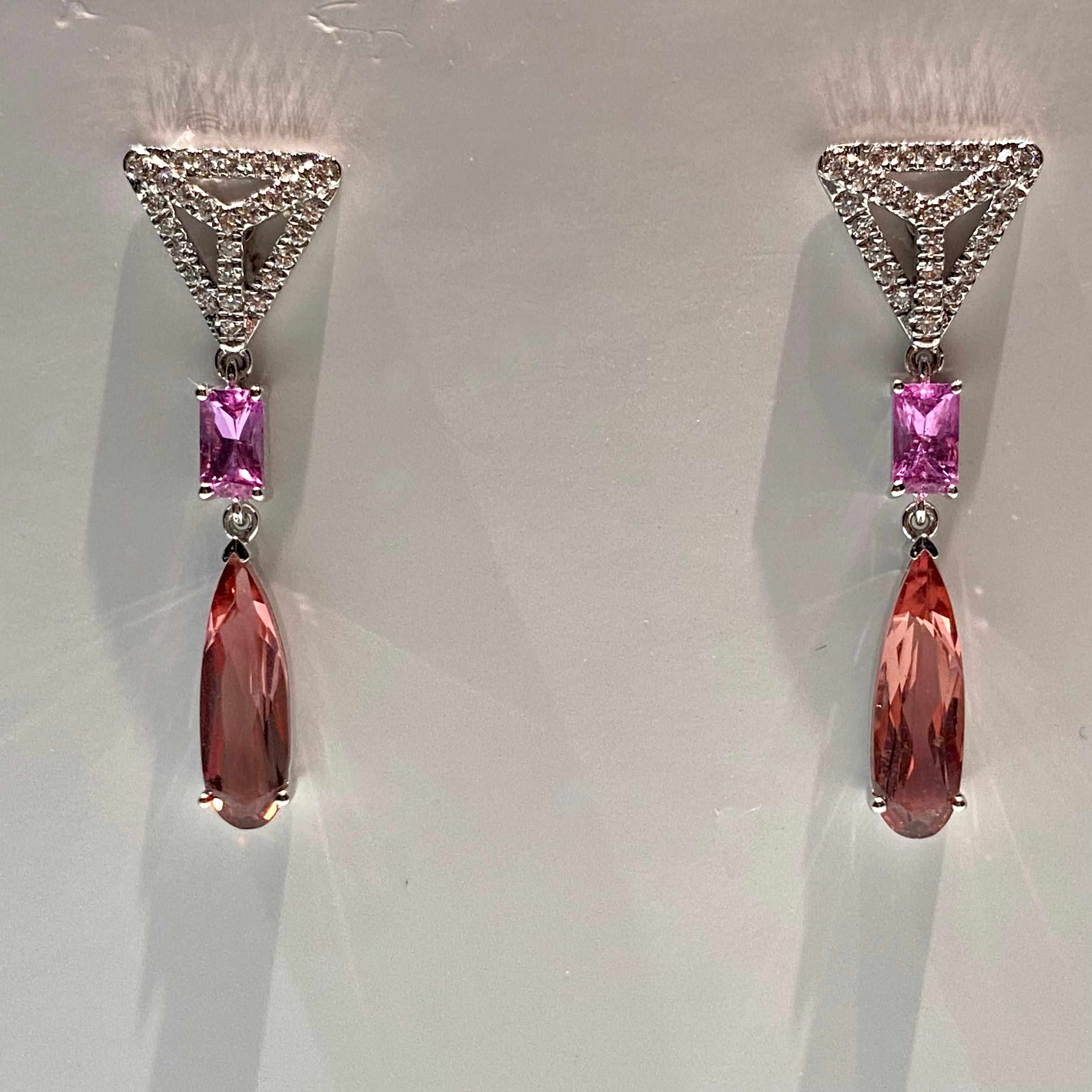 A pair of Art Deco Style earring. On each side of the earring there is a diamond encrusted triangle motif, followed by a Rectangle Pink Sapphire. Underneath the Sapphire dangles a elongated rain drop shape Tourmaline. This is a vintage style and is