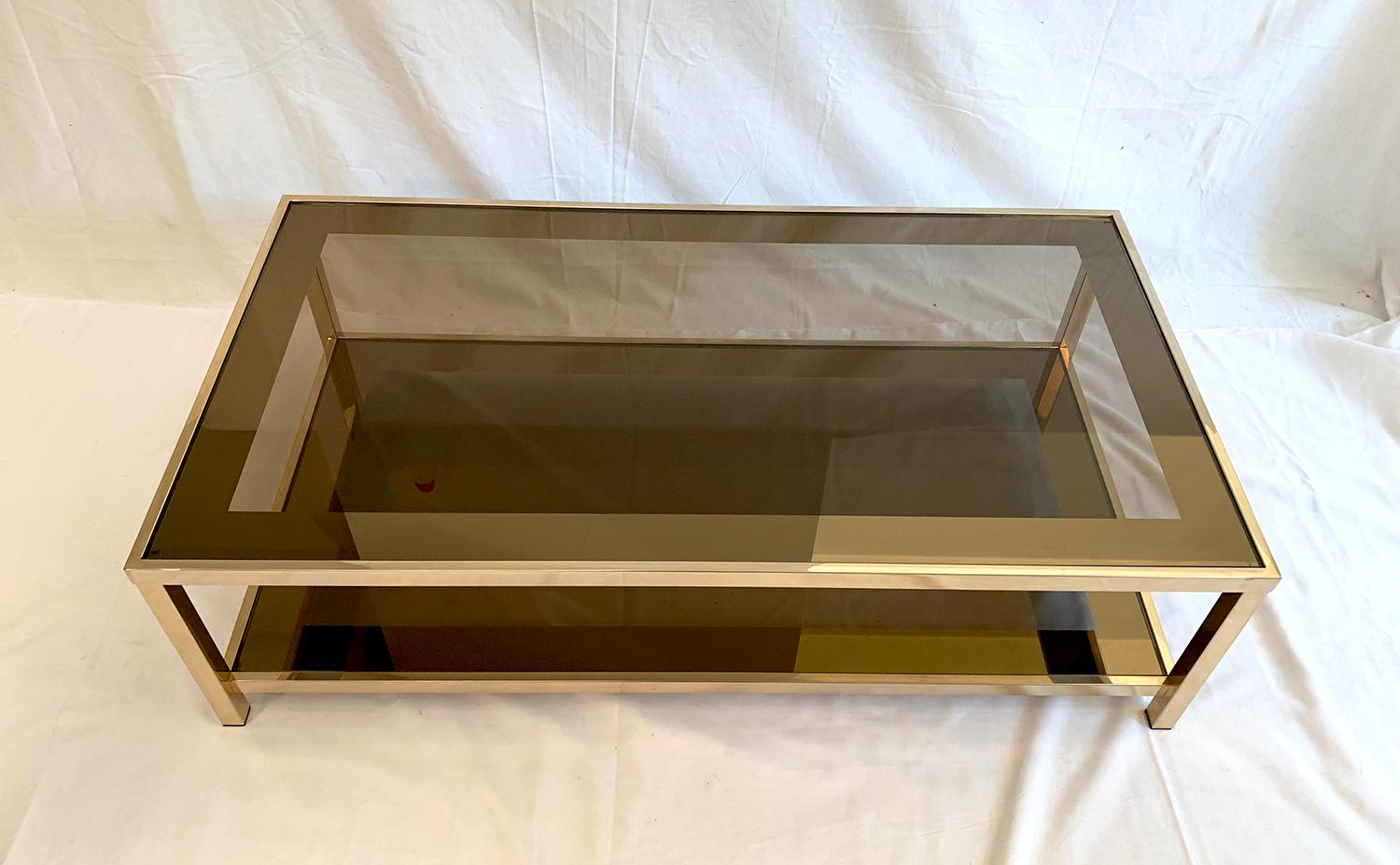 Beautiful coffee table with two levels designed and produced by Belgo Chrome, 1970s. The structure, gilded with 23-carat gold, showcases two trays of smoked glass lined with a wide bronze mirror band. The table is in very good