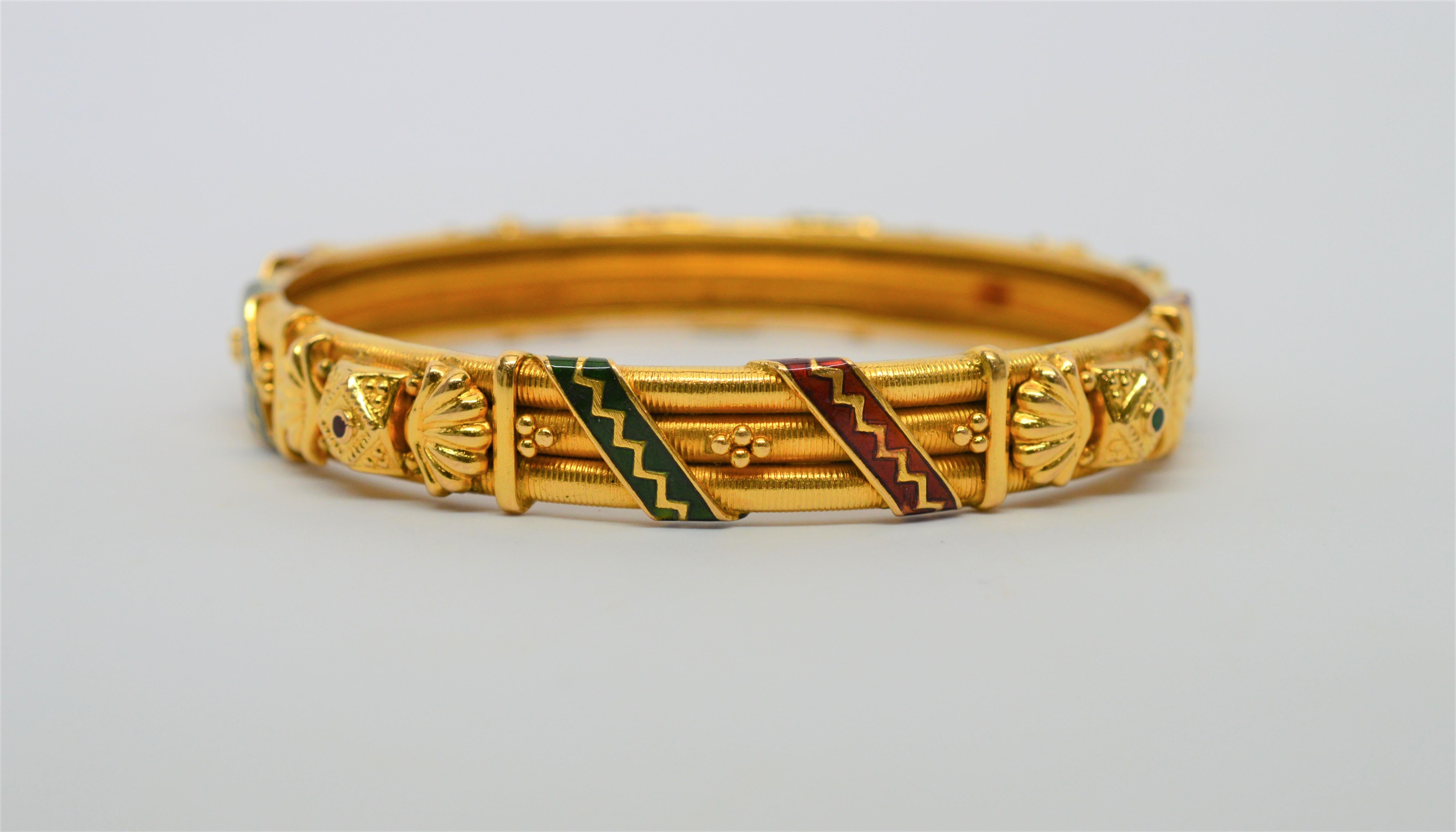 Crowned on four sides with ornate three dimensional medallions applied in 23 karat gold, this impressive triple-rimmed bangle bracelet is wrapped with hand applied red & green enamel ribbons. Measures a 7 inch circumference and 2-3/8 inch diameter