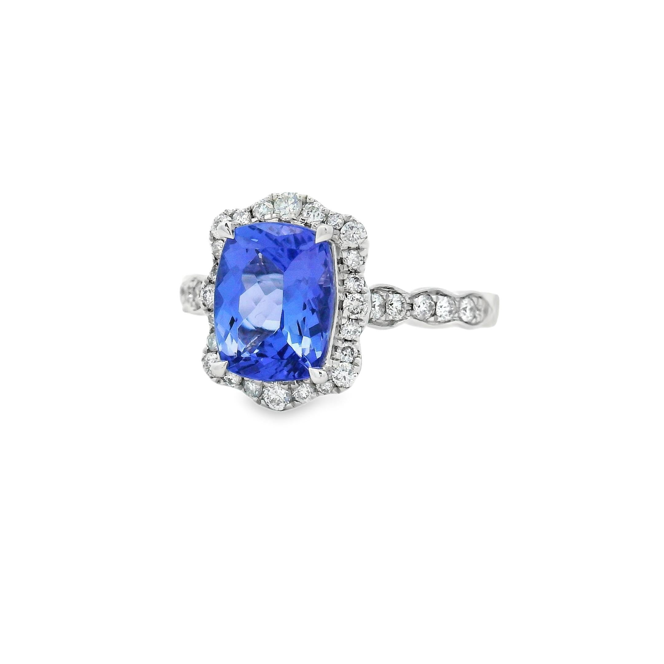 Dieser auffällige Cocktailring zeigt einen 2,30-karätigen Tansanit im Kissenschliff mit einer Größe von 9x7 mm, der von einem funkelnden Diamantenkranz umgeben ist. Der lebhafte violett-blaue Farbton des Mittelsteins wird durch 36 runde Diamanten im