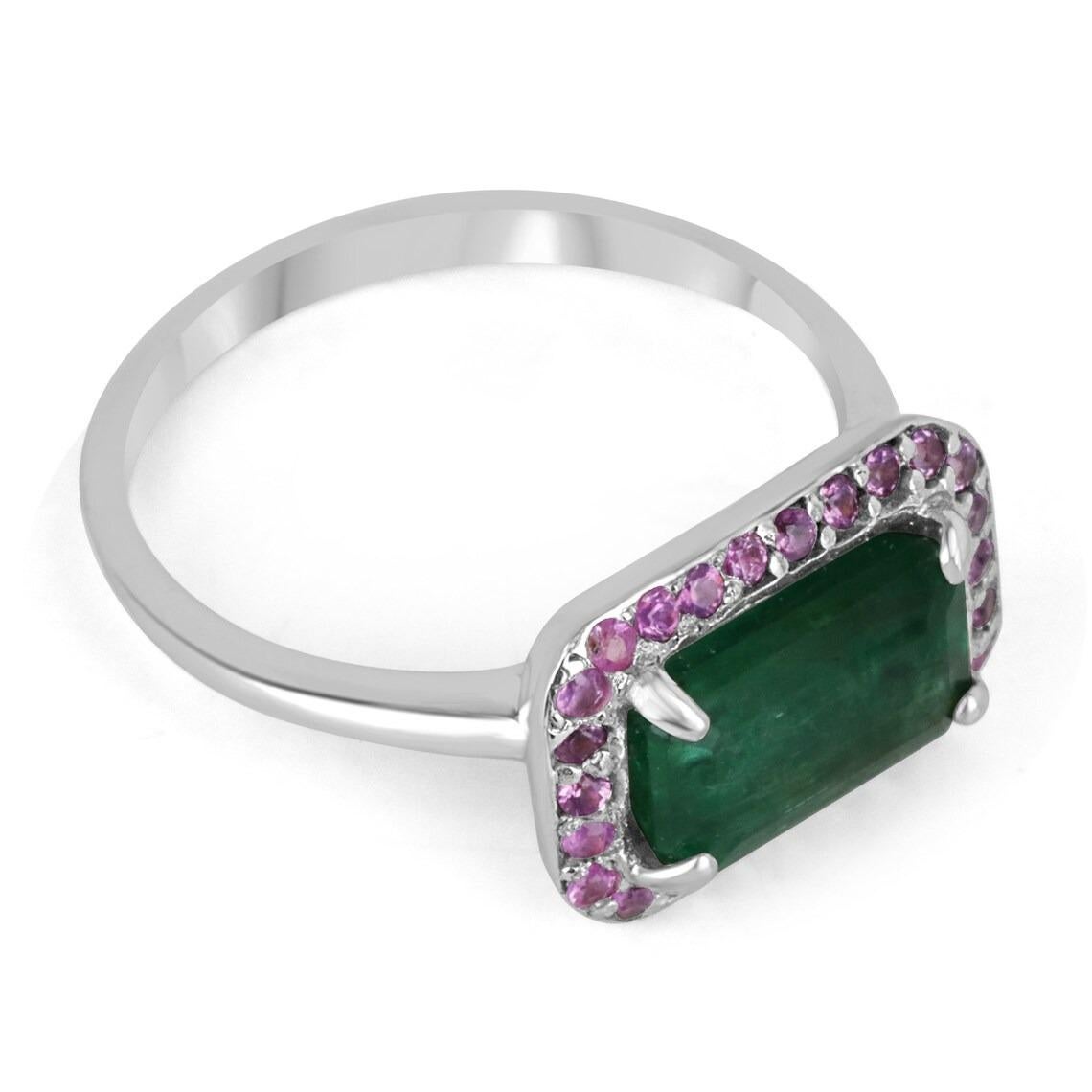 A stunning East to West emerald & pink sapphire 14K white gold ring. The center stone features a beautiful 1.90-carat, natural emerald cut. The gemstone has a desirable dark green color, with good eye clarity. Set east to west; surrounded by a round