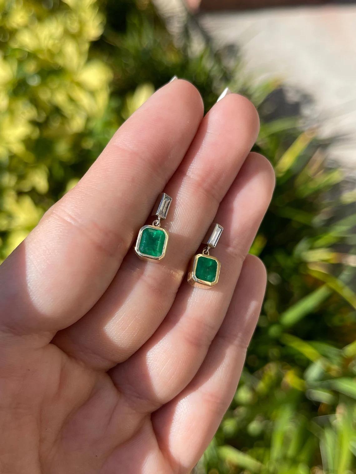 Displayed is a stunning pair of emerald and diamond, dangle earrings. Two gorgeous Zambian emerald-Asscher cuts totaling a full 1.90-carats, accented by two diamond baguettes. Set in simple prong settings, allowing for the emeralds and diamonds to