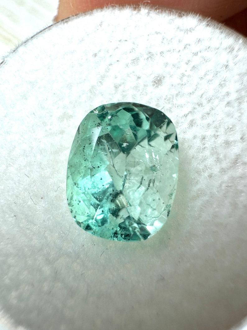 Stone: Emerald
Weight: 2.31-carats
Shape: Cushion Cut
Clarity: Transparent
Luster: Excellent-Very Good
Color: Light Green
Measurements: 9.24mm x 7.42mm x 6.03mm
Geographic Origin: Colombia
Treatment: Natural, Oiling

Comments: Due to their growth