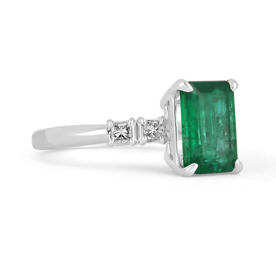 A stunning emerald and diamond engagement ring. The center stone features a four-prong set, 2.11-carat natural Zambian in emerald cut; displaying a rich dark green color and exceptional luster. Two princess-cut diamonds can be seen accenting both