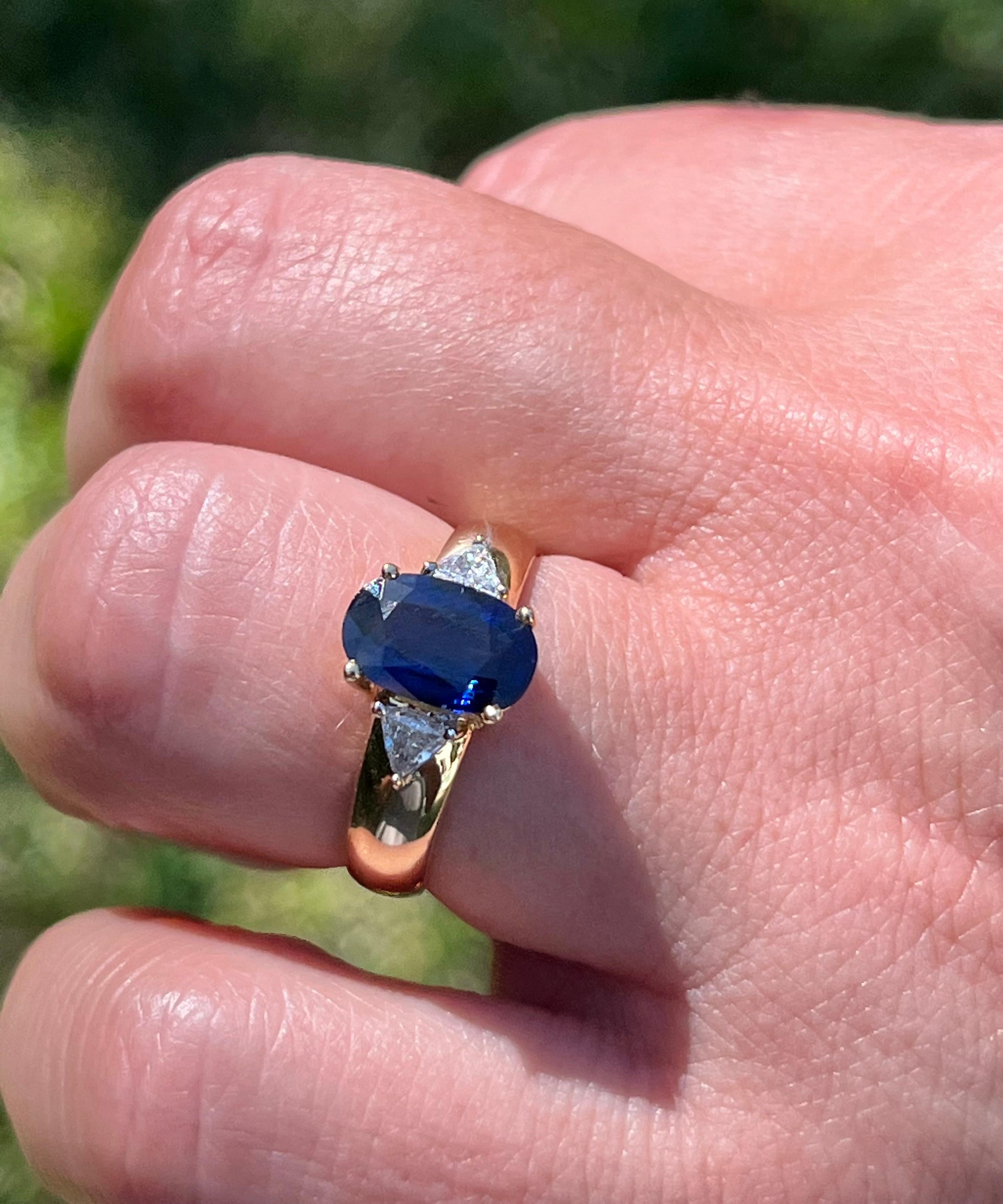 Modern 2.32 Carat Oval Cut Blue Sapphire with Trillion Cut Diamond Sidestones in 18k For Sale