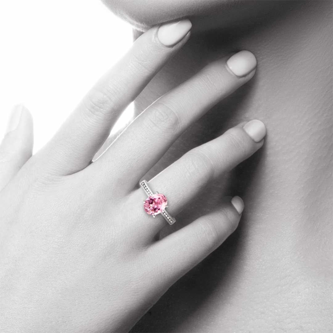 This solitaire engagement ring showcases a beautiful oval cut tourmaline in a mid pink colour set in four fine claws that are almost not there. The setting is elegantly finished by a fine channel set diamond band.. The Tourmaline weighs 2.32 carat