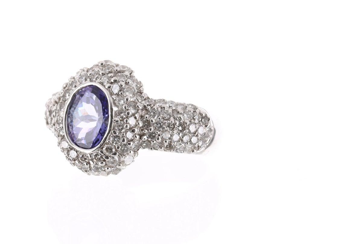 Displayed is a stunning Tanzanite & Diamond pave ring that is full of gorgeous sparkle from all sides! 106 fully faceted round cut diamonds are set in this ring creating a sea of glamor in this classically designed piece. Created in solid 14K white