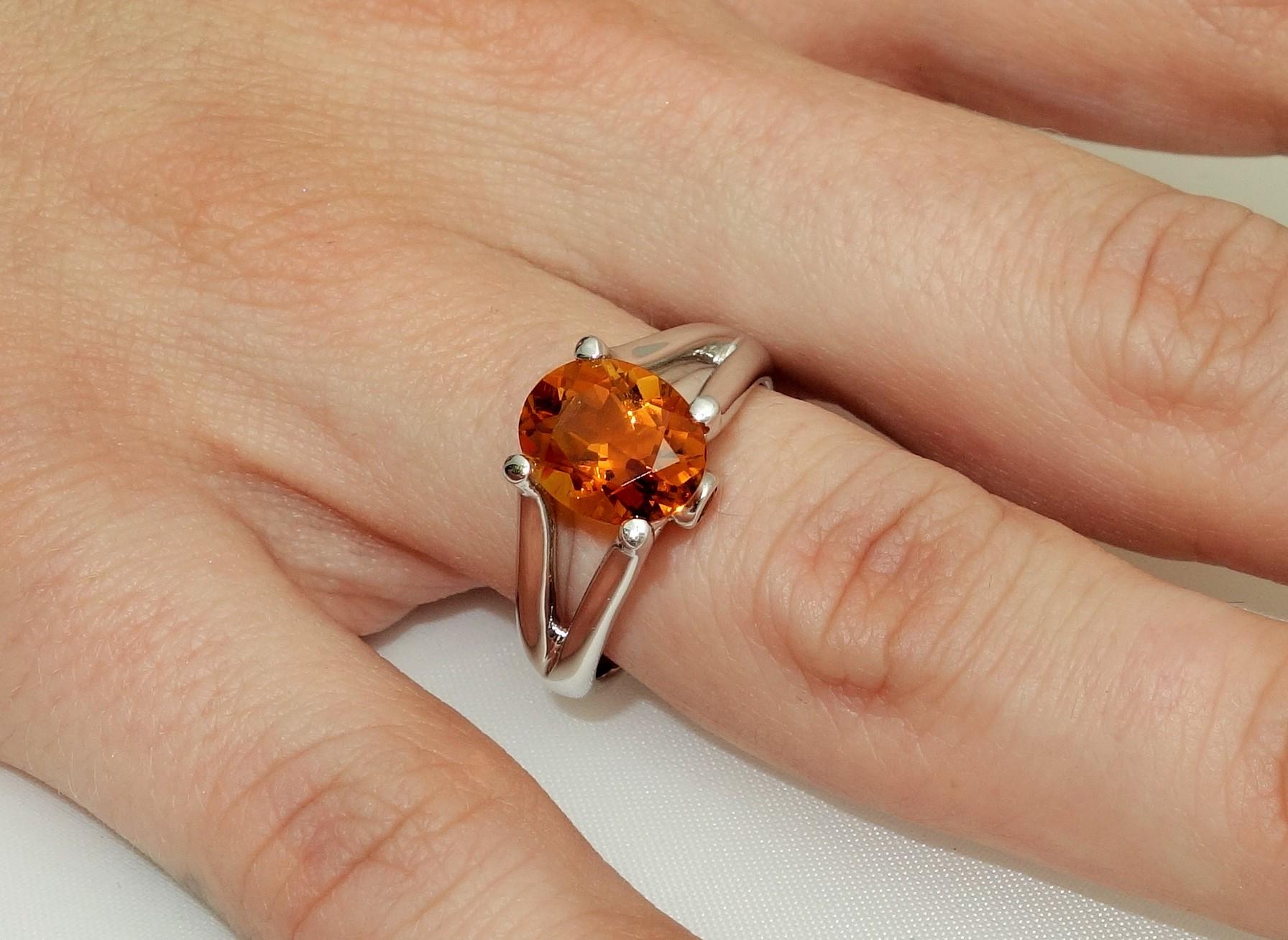 Beautiful ring featuring a 2.33 Carat oval Citrine in center enhanced with Sapphires; approx. 0.07tctw; Sterling Silver Tarnish-resistant Rhodium mounting; Size 8, we offer ring re-sizing. Stylish and Classy…illuminating your look with Timeless