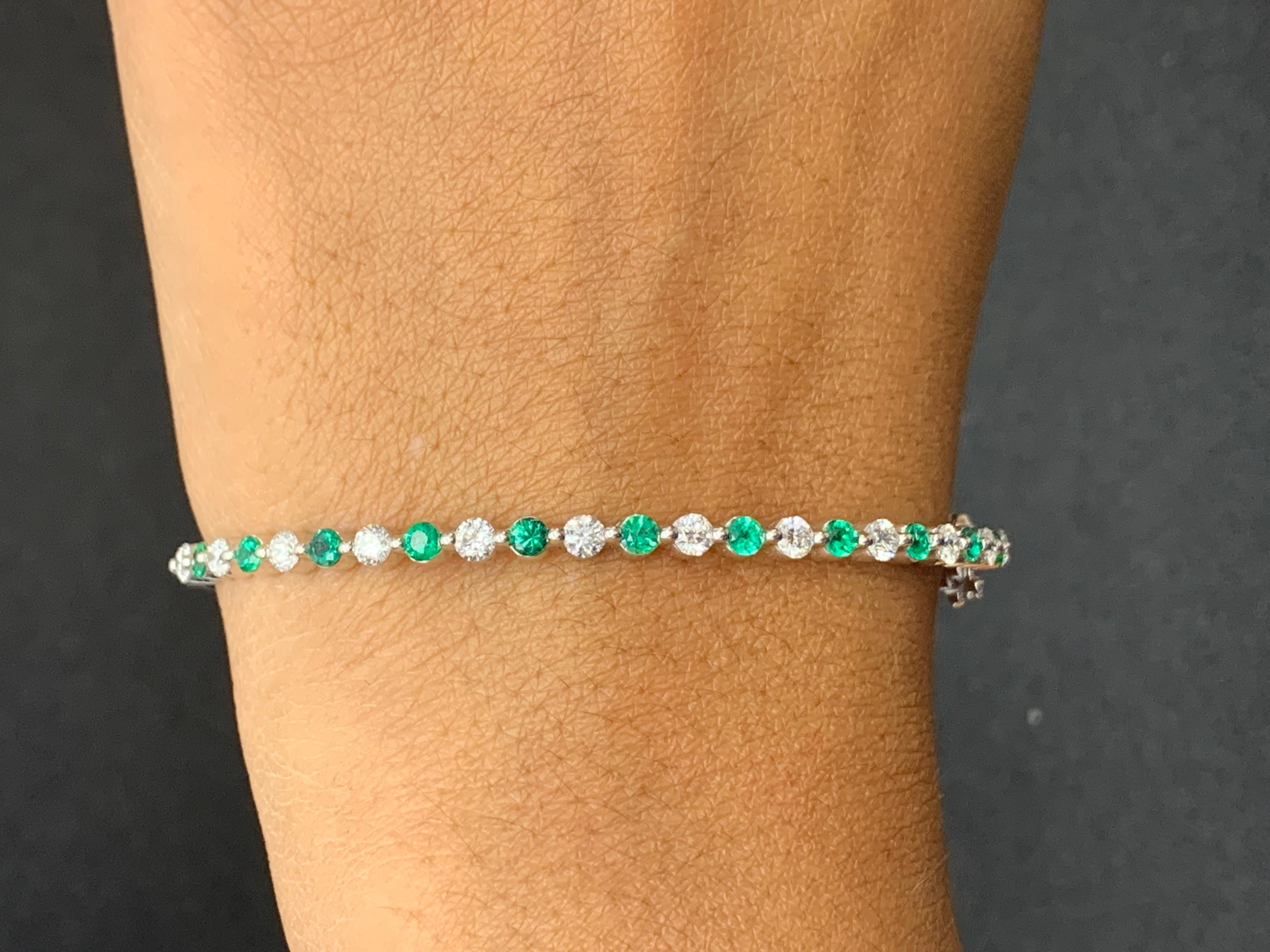Sparkle in the spotlight with this Emerald and diamond bangle bracelet. Features 16 full-cut round emeralds weighing 2.33 carat and 15 diamonds weighing 0.40 carat. each elegantly set in a 14k white gold basket. . A hinged design bracelet for easy