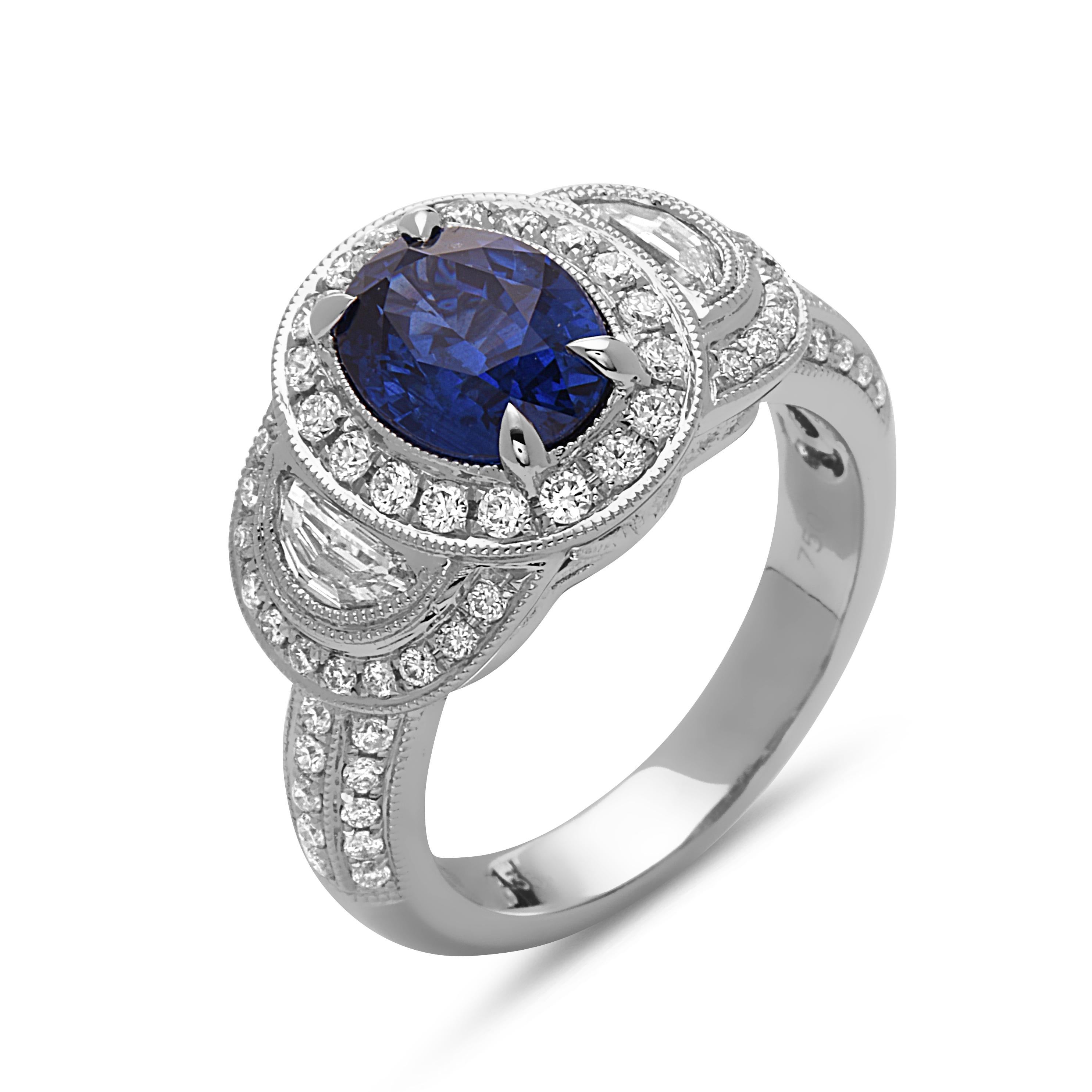 Dieser atemberaubende Cocktailring zeigt einen schönen ovalen Saphir von 2,33 Karat mit einem Diamant-Halo auf einem Halbdiamant-Schaft. Der Saphir wird auf beiden Seiten von einem Halbmond-Diamanten flankiert. 

Dieser Ring ist in 18K Weißgold