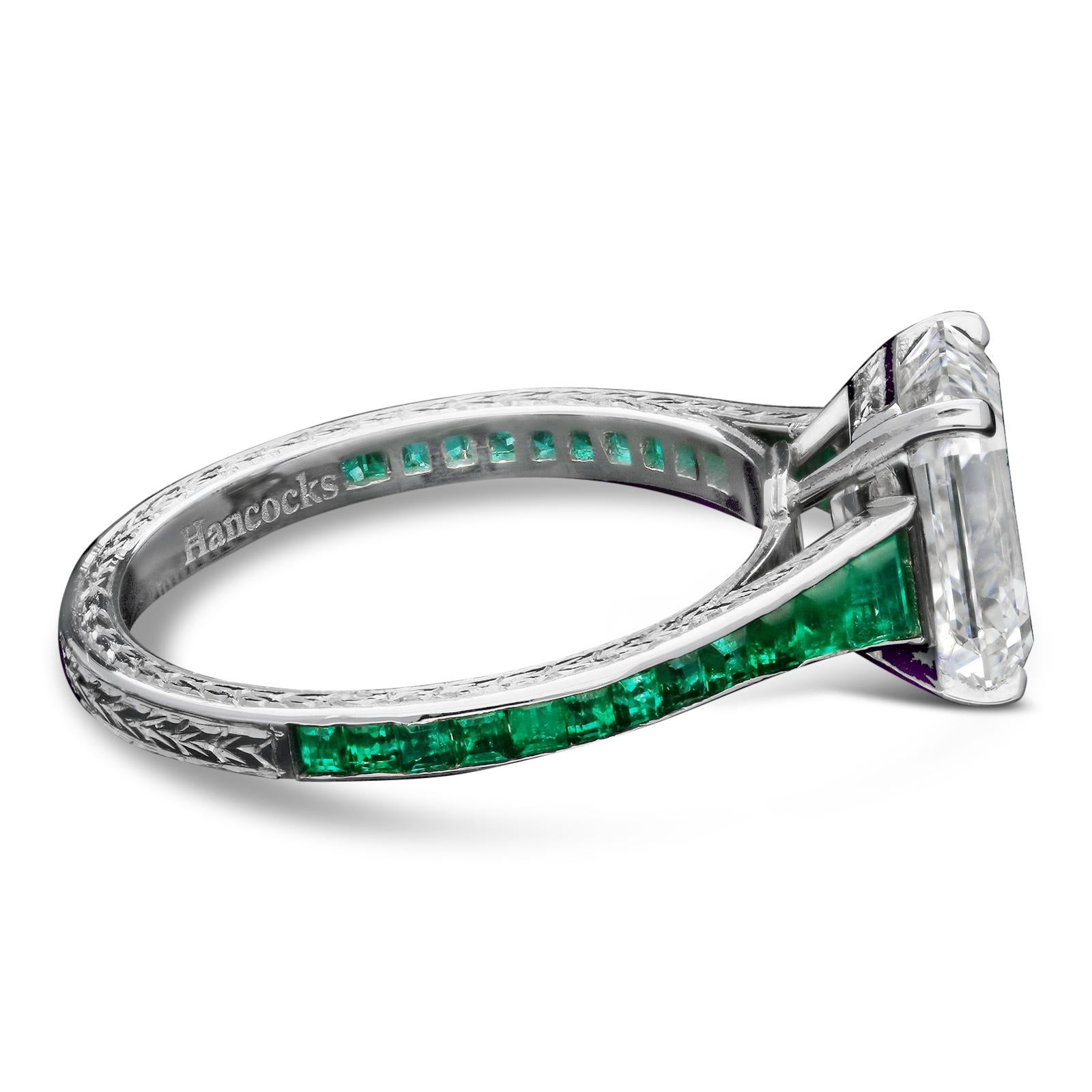 A beautiful diamond and emerald ring by Hancocks set to the centre with a lovely old Vintage emerald-cut diamond weighing 2.34ct and of F colour and VS2 clarity in a corner claw setting, the fine tapering band channel-set with calibre cut emeralds,