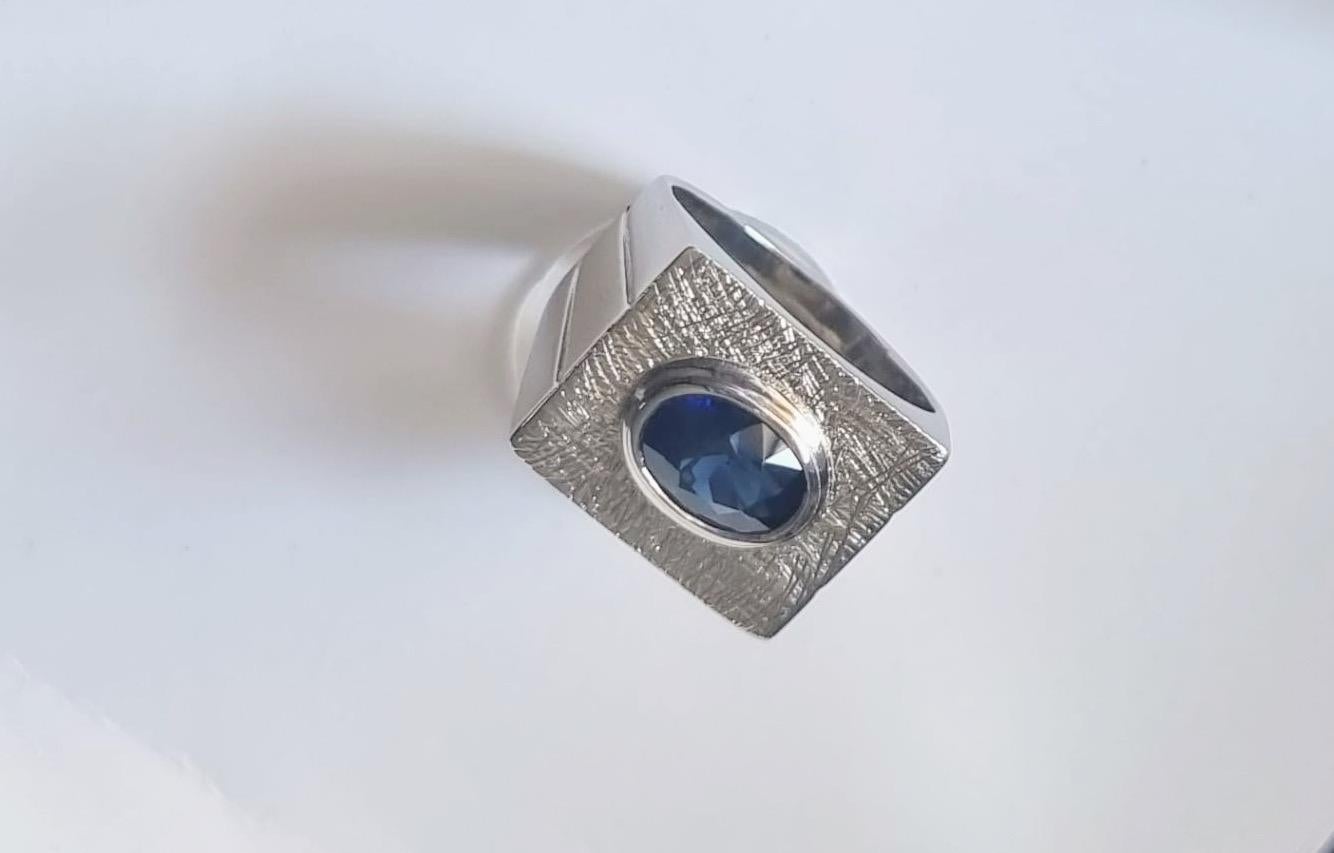 Introducing our elegant 2.34-carat Oval Blue Sapphire Signet Ring in heavy rhodium plated sterling silver metal, a timeless piece that combines classic design with modern sophistication. This ring features a stunning oval-cut blue sapphire, known
