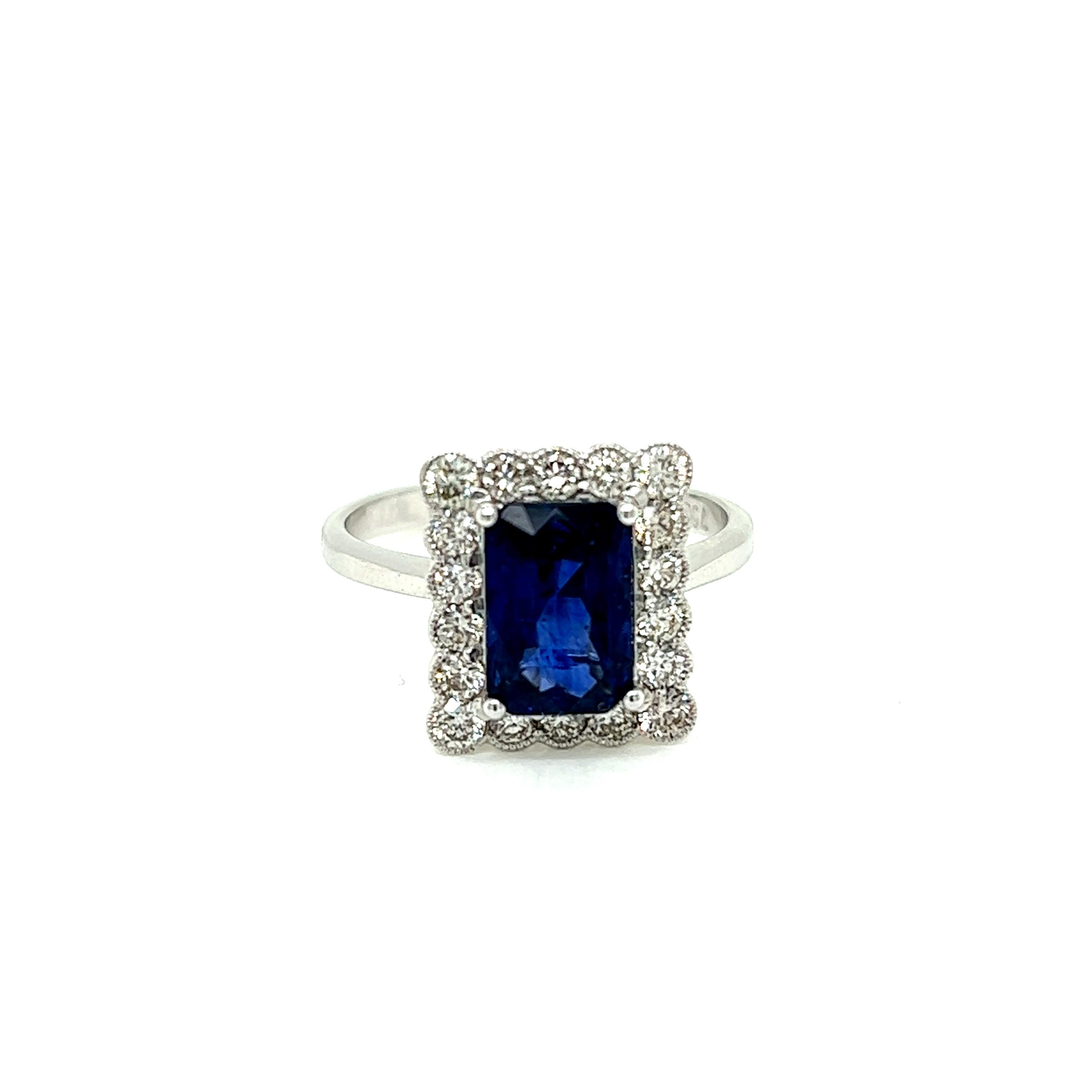 This alluring ring features a resplendent 2.35 carat Blue Sapphire at its centre. Surrounding this precious emerald cut stone are 18 Round Brilliant Diamonds set in 18K White Gold.

The Diamonds in the ring weigh a total of 0.58 carats and are of H