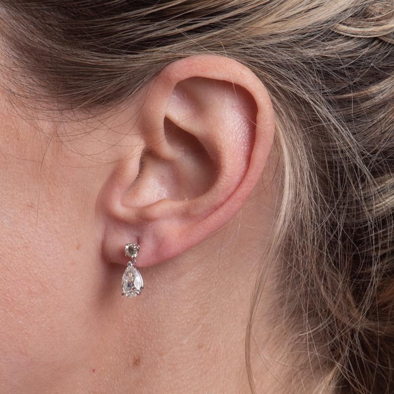 These petite diamond earrings feature 2.35 carat total weight in pear shaped diamonds that dangle from 0.30 carat total weight in round diamonds. They are set in 14 karat white gold with friction post and back. These are delicate to wear everyday
