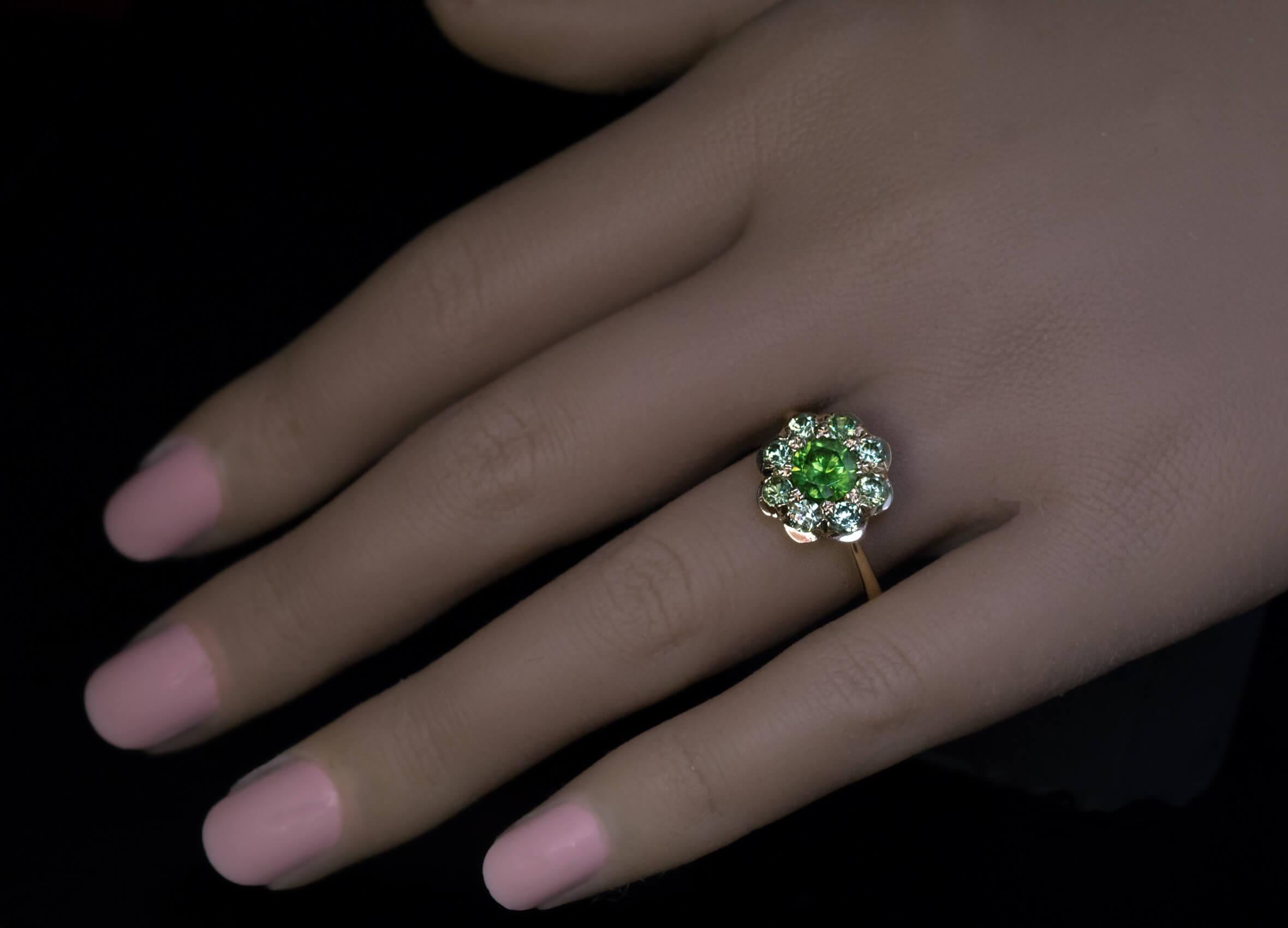 This contemporary custom made 18K gold cluster ring features sparkling Russian demantoids from the Ural Mountains.  The ring is centered with a 1.10 ct demantoid of a medium green color surrounded by eight light green small demantoids (1.25 carats