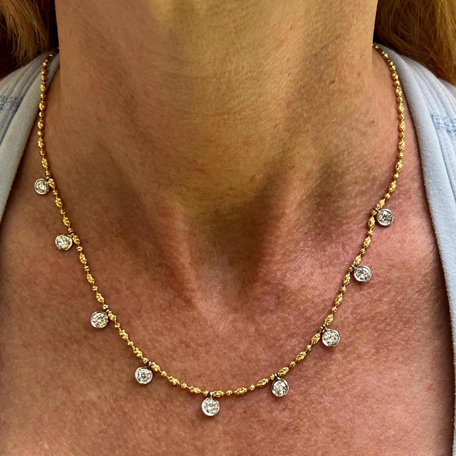 Modern diamond drop necklace crafted in 14 karat yellow and white gold. The necklace features 9 round brilliant cut diamond drops bezel set in white gold. The diamonds weigh 2.35 CTW and are graded G-H color and VS2- SI1 clarity. The diamond cut