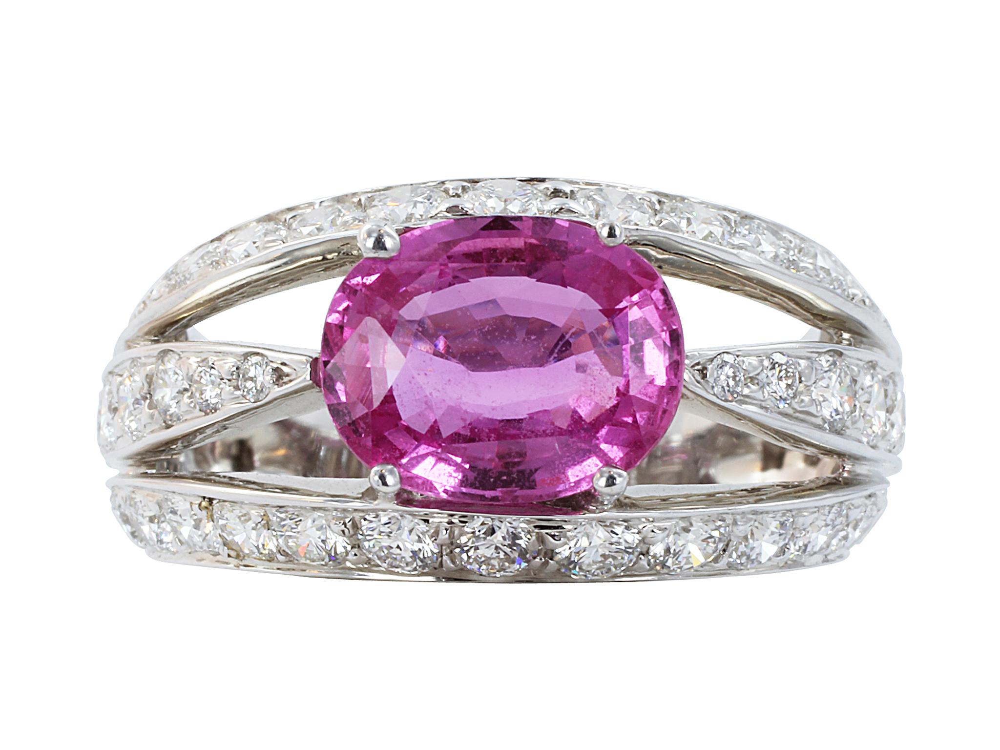 18 karat white gold ring with a split shank consisting of 1 oval prong set pink sapphire weighing 2.36 carats and accented by bead set round brilliant cut diamonds having a total weight of 1.57 carats and approximate color and clarity of F-G/VS1-VS2.