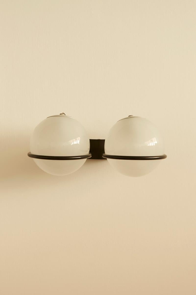 Pareja de apliques dobles, modelo 237/2, diseñados en 1970 y fabricados por Arteluce. Con globos de vidrio esmerilado recubiertos de metal lacado, estas lámparas encarnan un diseño elegante y arquitectónico. Incluye la etiqueta original de