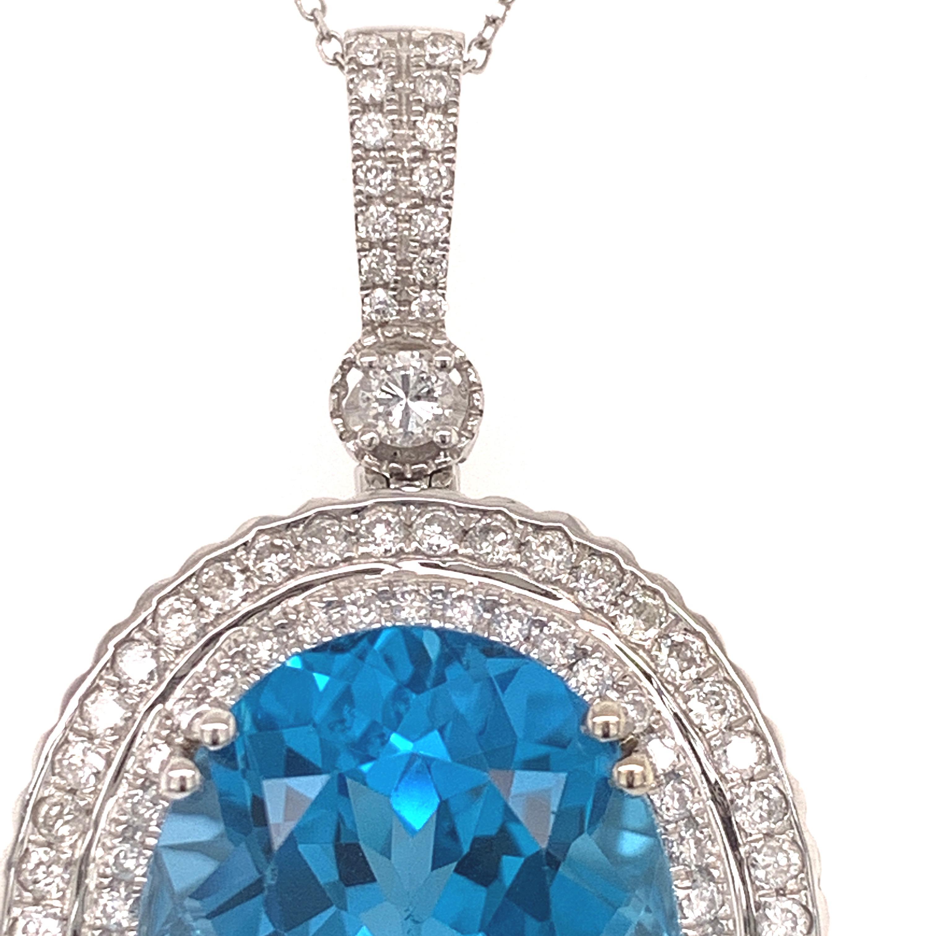 Elegant topaz diamond pendant. Oval faceted, high brilliance, lively blue-sky blue, 23.71 carats topaz, encased in a basket mounting with eight bead prongs, accented with round brilliant cut diamonds on the bail and two rows surrounding the topaz. 