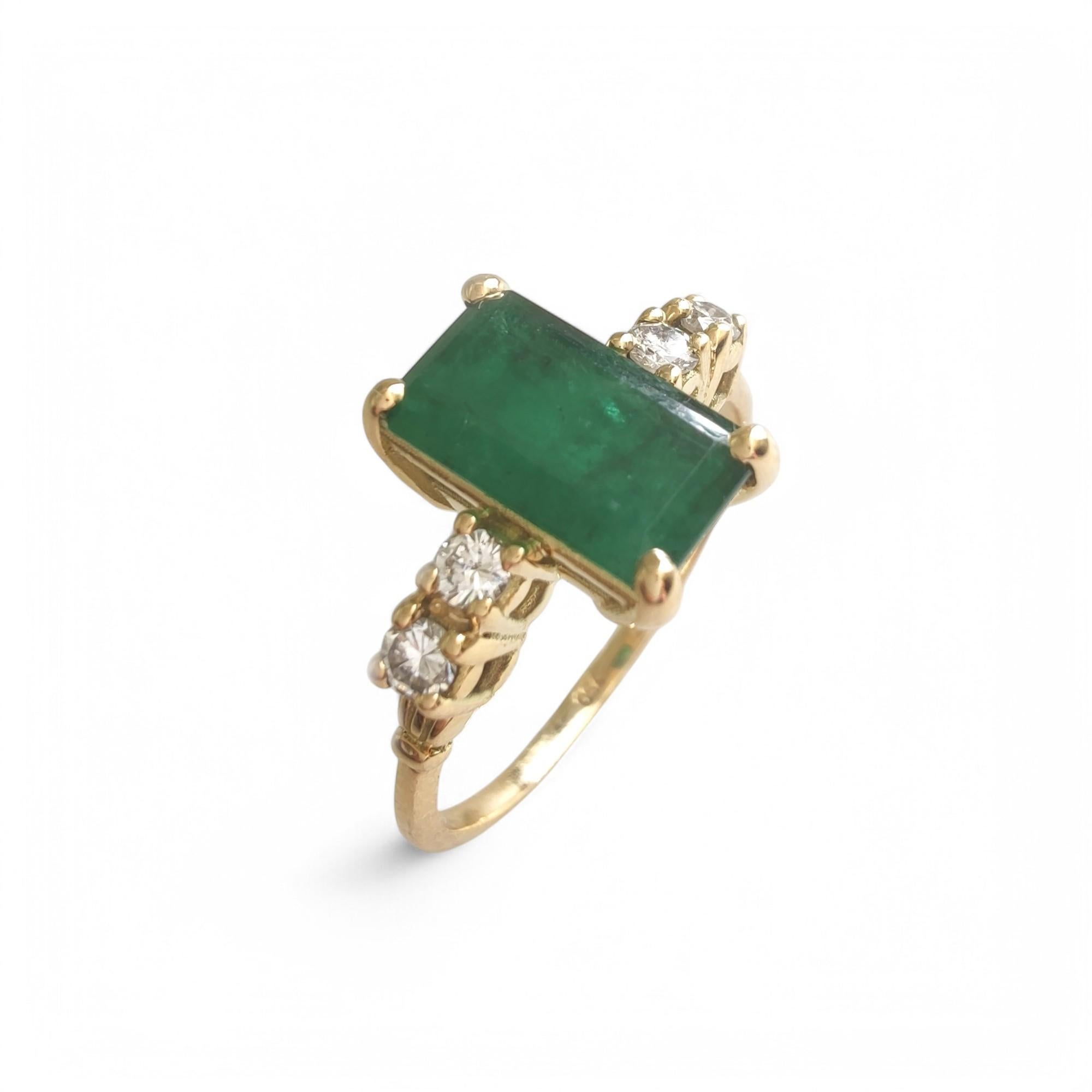 This exquisite emerald and diamond ring is crafted in solid 18K yellow gold, featuring a rich emerald-cut natural emerald at its center. Known for its vivid color and brilliance, the emerald is complemented by four round brilliant-cut natural