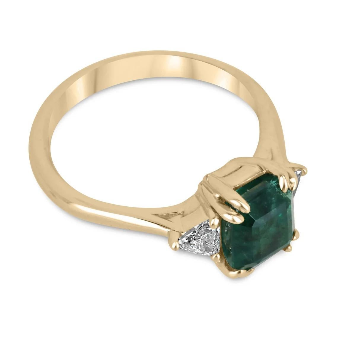 A classic emerald and diamond three-stone ring. This magnificent piece features a remarkable Asscher cut emerald from the origin of Zambia as the center stone. The gem displays a dark, desirable emerald green color with very good transparency and