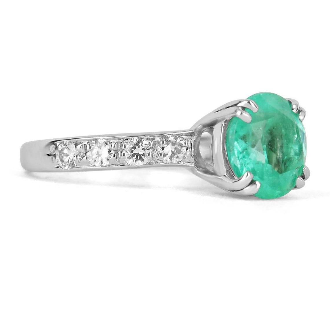 Elegantly displayed is a natural, round Colombian emerald and diamond accent engagement ring. The center gem is a round emerald filled with life and brilliance! Among the emeralds impressive qualities are its vibrant color and beautiful eye clarity.