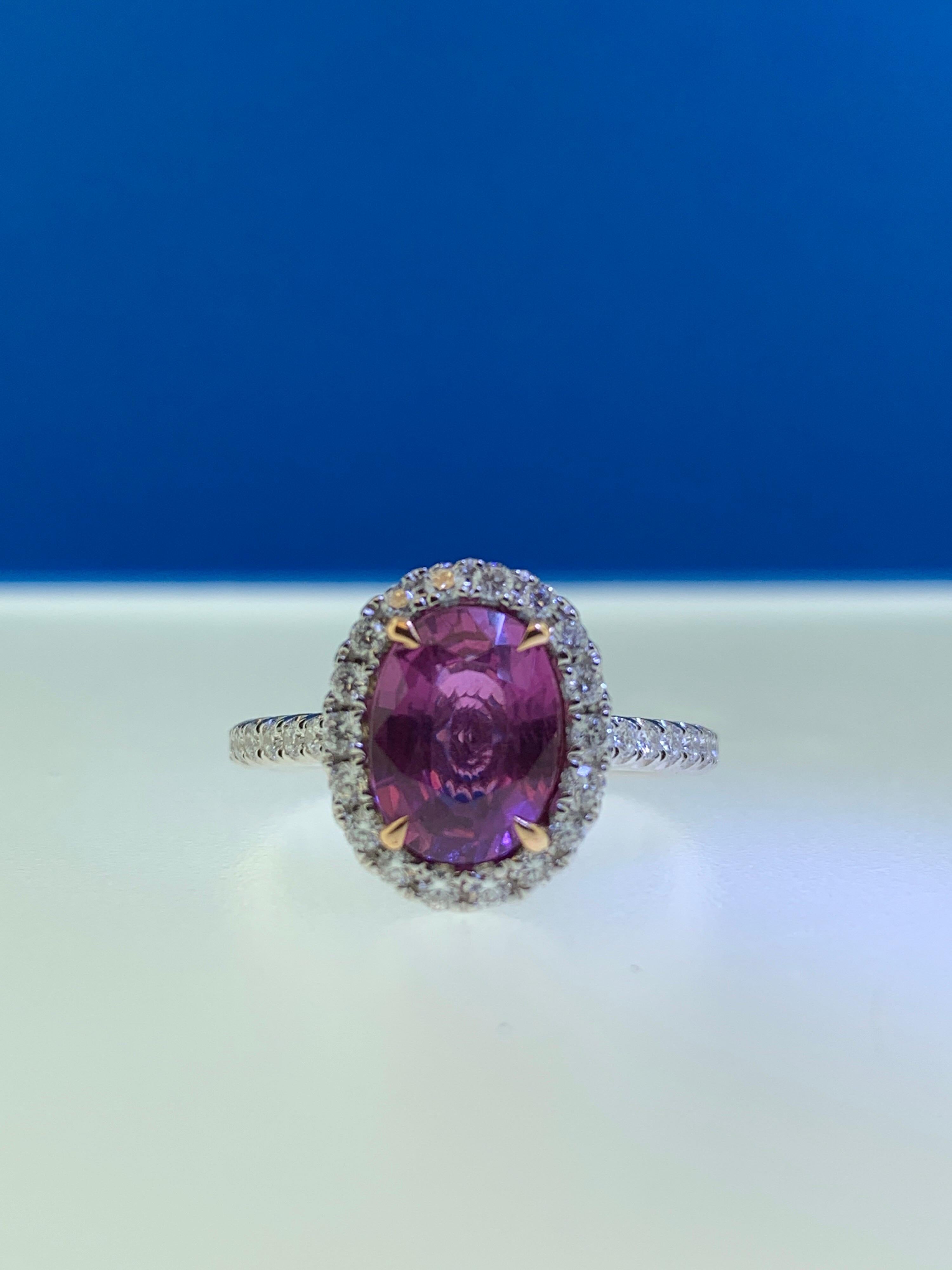 This stunning ring showcases a beautiful 2.39 carat oval pink sapphire with a white diamond halo set in 18 karat white gold with rose gold prongs on the sapphire. Total diamond weight = .44 carats. Ring size is 6 1/2.
