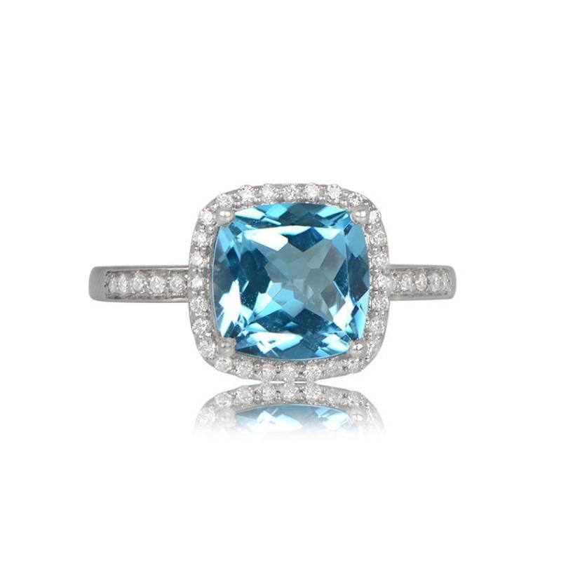 Elevate your style with this exquisite 18k white gold ring, showcasing a brilliant 2.39-carat cushion-cut blue topaz held securely in prongs. The enchanting design includes a halo of round brilliant-cut diamonds, elegantly pave-set along the