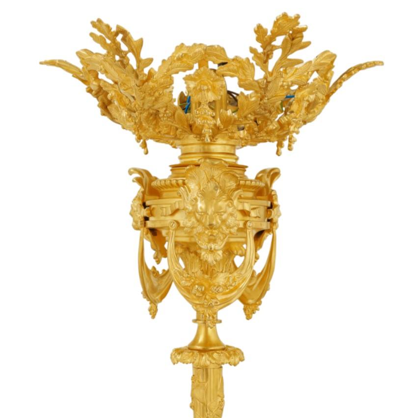 Questo eccezionale lampadario, magistralmente realizzato in ottone finemente cesellato e sontuosamente dorato in oro a 24 carati, è una testimonianza della duratura eleganza dello stile Luigi XVI, arricchito da profonde influenze classiche. Il