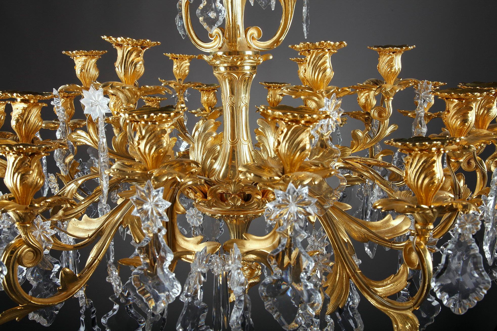 This monumental crystal and ormolu chandelier was designed in Louis XV style. Oversized, luminous slice-cut drops and pendants hang from scrolling Rocaille branches crafted of gilt bronze. With its organic swirls and curves of scrolls and acanthus