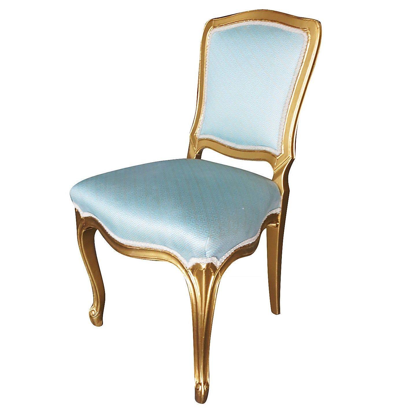This set of 24 dining room side chairs were manufactured in the 1950s in a Louis XVI-style Hollywood Regency design and finished in gold leaf color, featuring blue and gold colored fabric covers. Side Chairs

Extra chairs are available, please