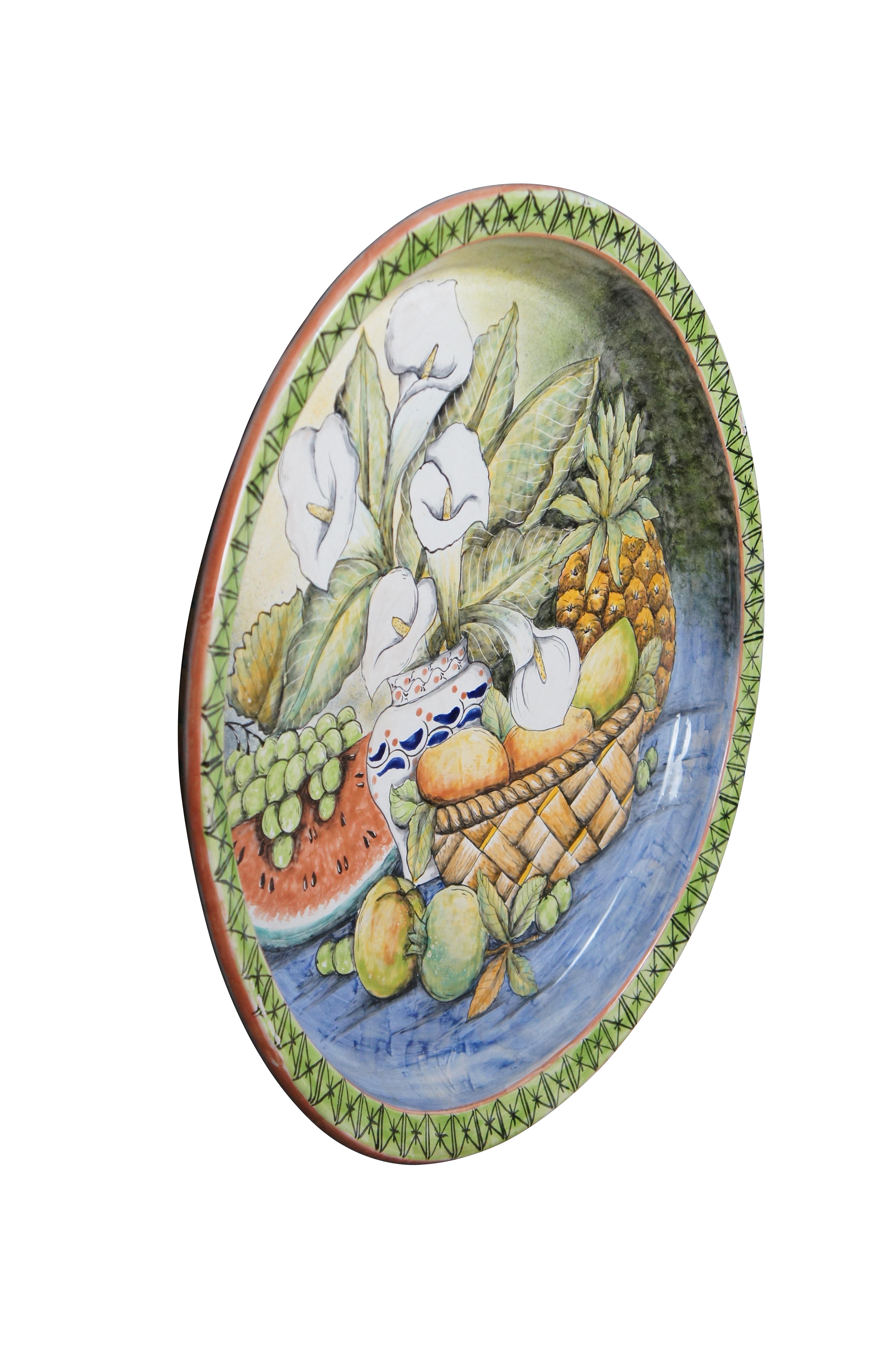 A beautiful 20th century Majolica Platter / Decorative Wall Plate. Made in Santa Rosa de Lima (Villagrán), Guanajuato. Features a hand painted still life with a basket of fruit besides a watermelon, grapes and a pineapple. In the center is a