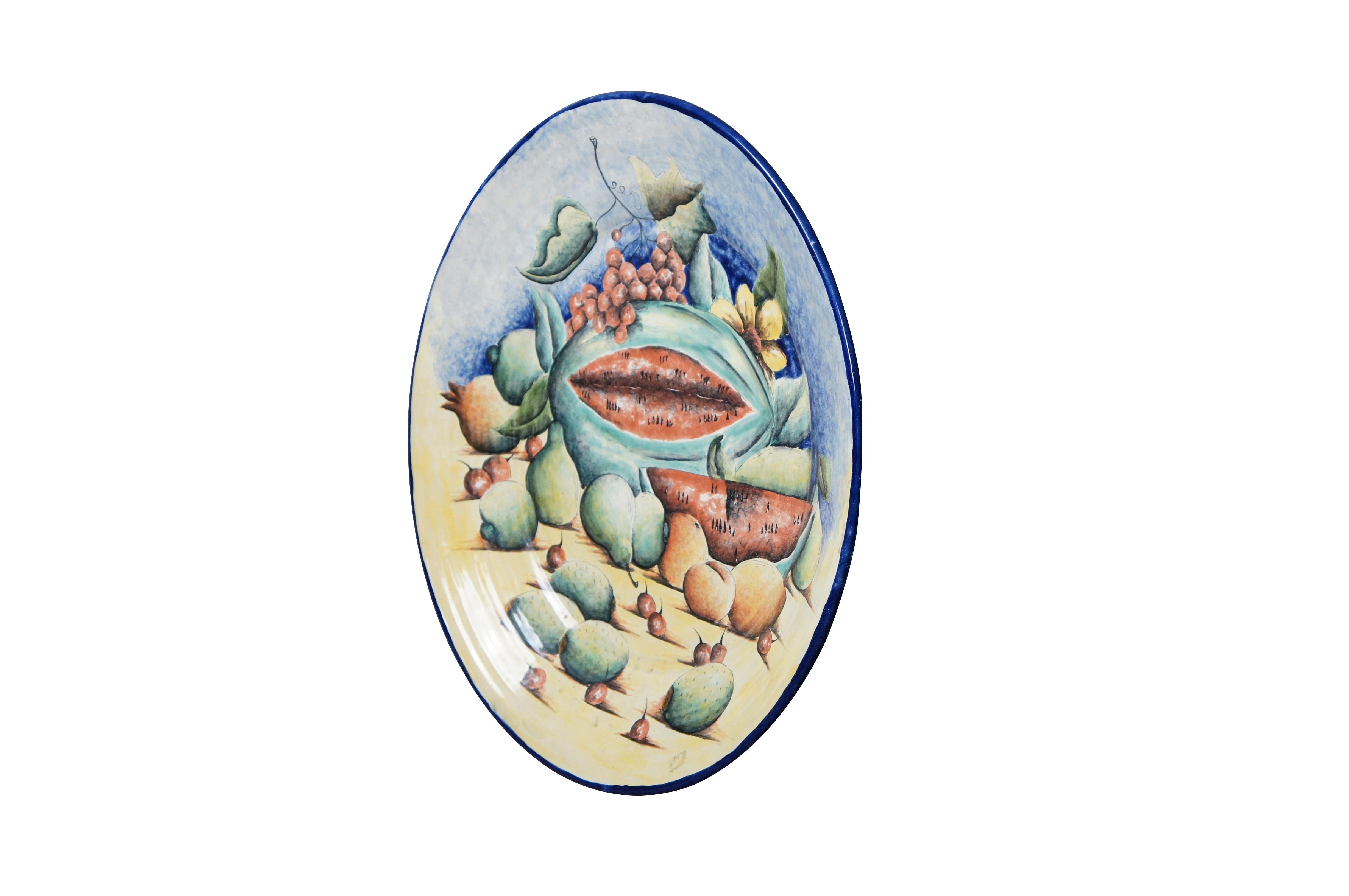 A beautiful 20th century Majolica Platter / Decorative Wall Plate. Made in Santa Rosa de Lima (Villagrán), Guanajuato. Features a hand painted still life of watermelon and other fruit. The foreground of the plate is blue along the top with a sand
