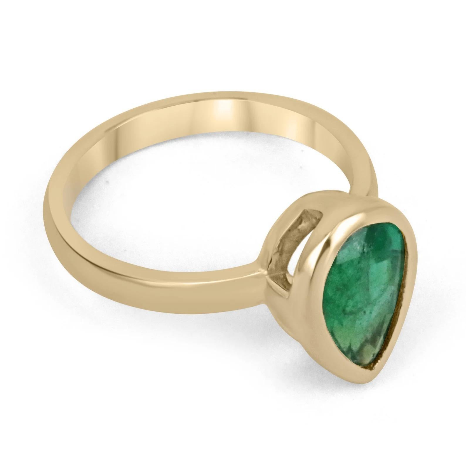 Displayed is a vivid green emerald bezel, teardrop solitaire ring in 14K gold. This gorgeous solitaire ring carries a full 2.40-carat emerald that has ideal color and excellent eye clarity. Minor imperfections are normal as this emerald is a