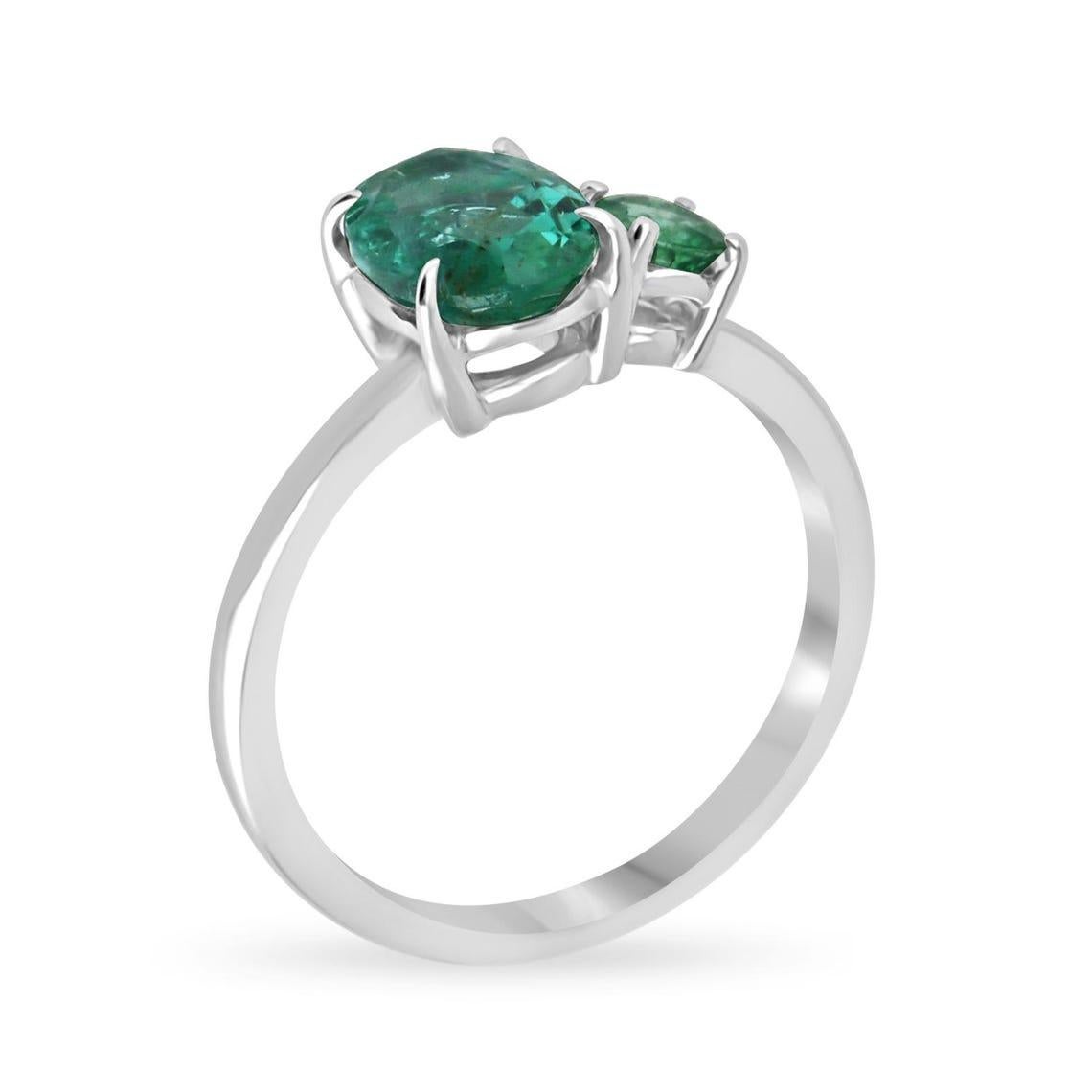 Elegant and unique, this Toi et Moi Emerald Ring features a striking duo of natural emeralds—one oval-cut with lush bluish-green undertones and one round-cut with a vivid, high-luster green hue. Set in a timeless 14K white gold band, each gemstone