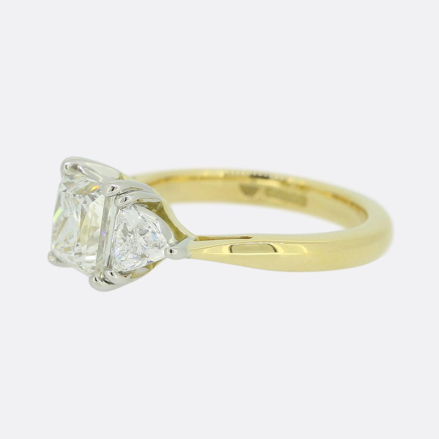 This is a contemporary 18ct yellow gold diamond three stone ring. The centre stone is a stunning 1.50 carat princess cut diamond which is flanked by a smaller trillion cut diamond on each shoulder. The diamonds have been expertly matched for colour