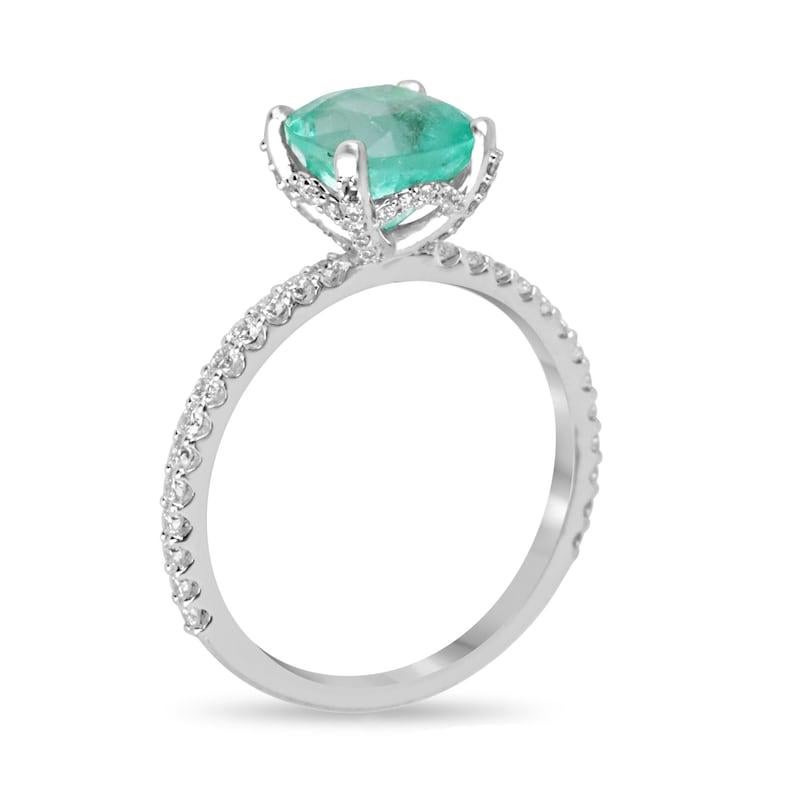 Indulge in the allure of our Emerald and Diamond Ring, where a stunning 2-carat cushion cut emerald takes center stage, cradled in a secure four-prong setting. The shank, gallery, and prongs are adorned with diamonds, adding a touch of brilliance