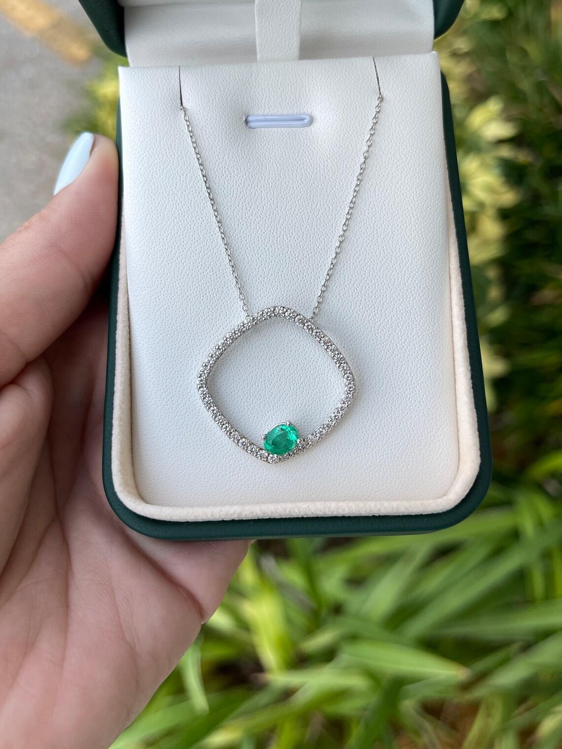 Pendentif moderne en or blanc 14K avec émeraude naturelle et diamant en forme de coussin flottant. Fabriquée à la main en or blanc massif, cette pièce unique ne manquera pas de faire parler d'elle. Les diamants blancs sertis en pavé sont disposés