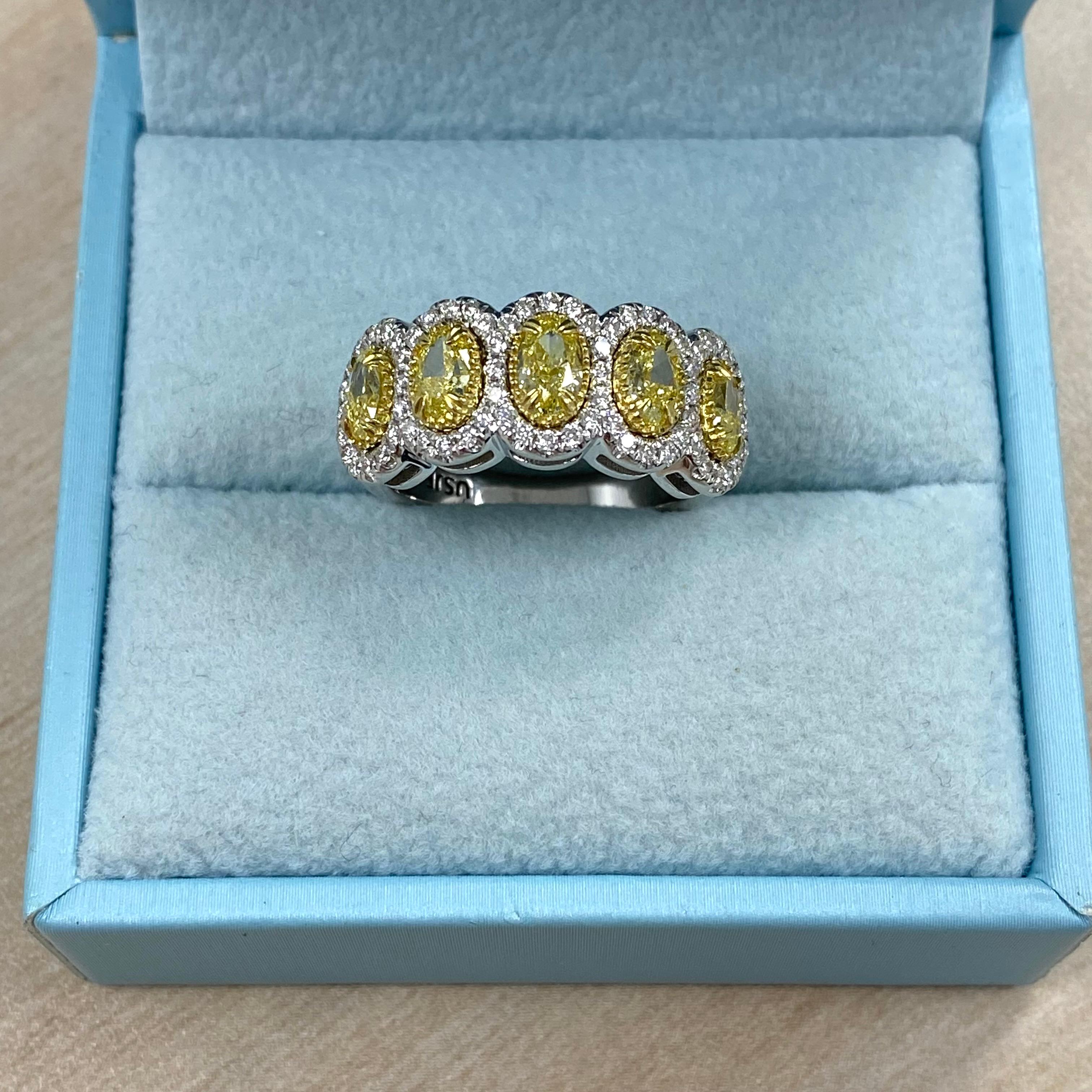 This dazzling wedding band features five natural fancy light yellow oval cut diamonds with SI1/SI2 clarity, totaling 1.93 carats, each individually edged in a colorless micro pave halo of round cut diamonds, G/H color and VS/SI clarity, with a total