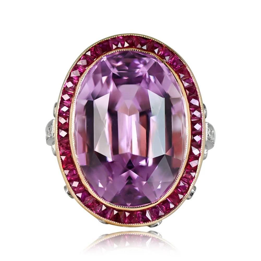 This stunning ring showcases a natural 24.10-carat oval-cut Kunzite, exhibiting exceptional pink color saturation. The center kunzite is gracefully surrounded by a halo of French-cut rubies, adding a touch of sophistication. The under gallery
