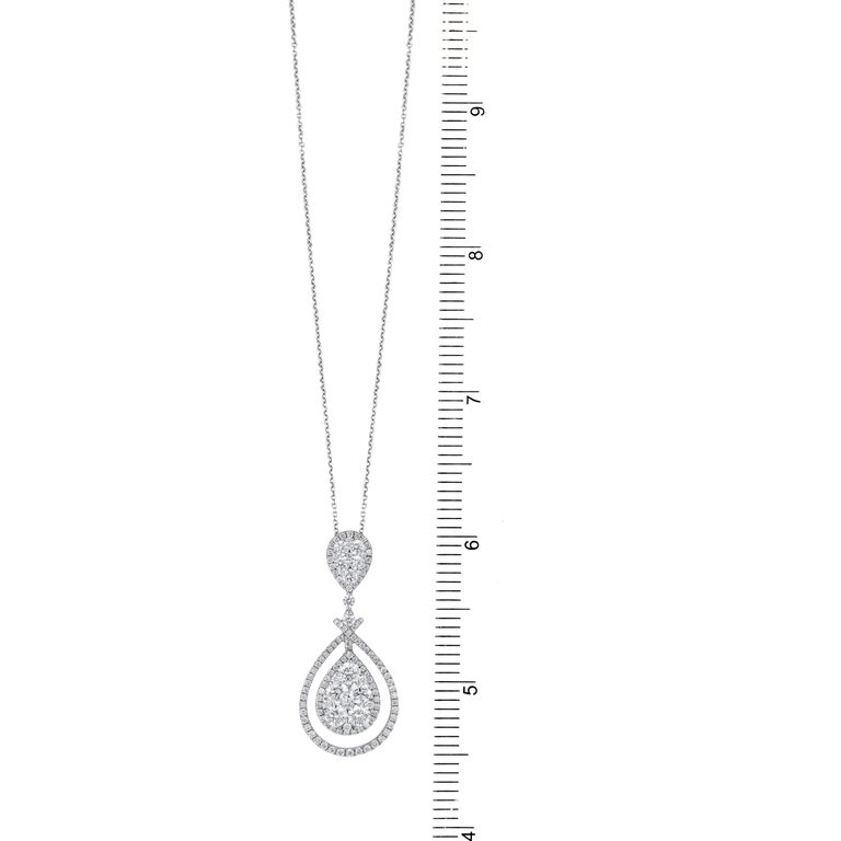 This delicate pendant has clusters of round white diamonds, carefully set to give the impression of a large pear shape pendant. This dangles from additional round diamonds, ending in a bail that is an inverted illusion pear. The total diamond weight