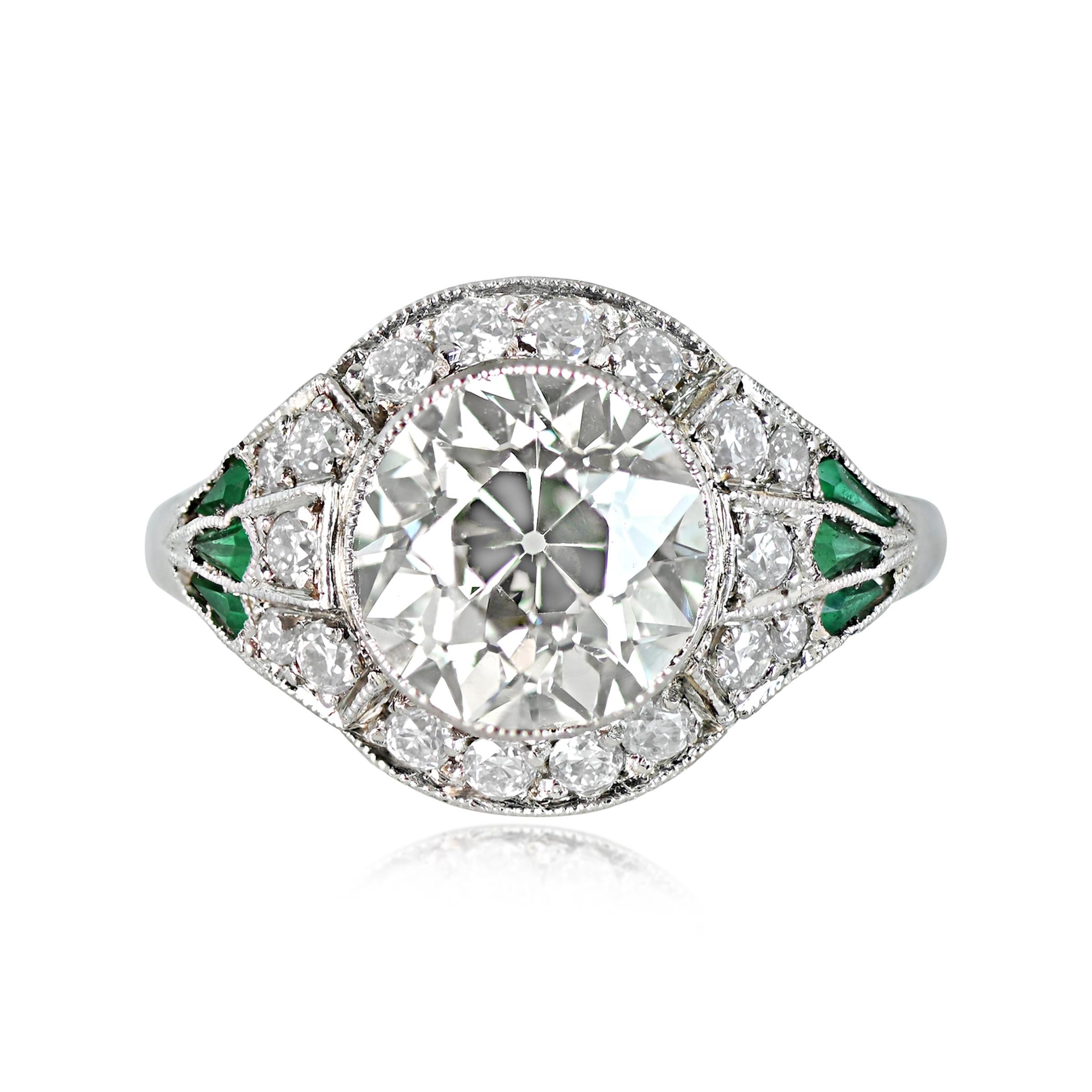 This Art Deco-style engagement ring is decorated and showcases a 2.42-carat old European cut diamond with M color and VS2 clarity. The center diamond is surrounded by an old-cut diamond halo, and the shoulders feature kite-shaped natural emeralds.