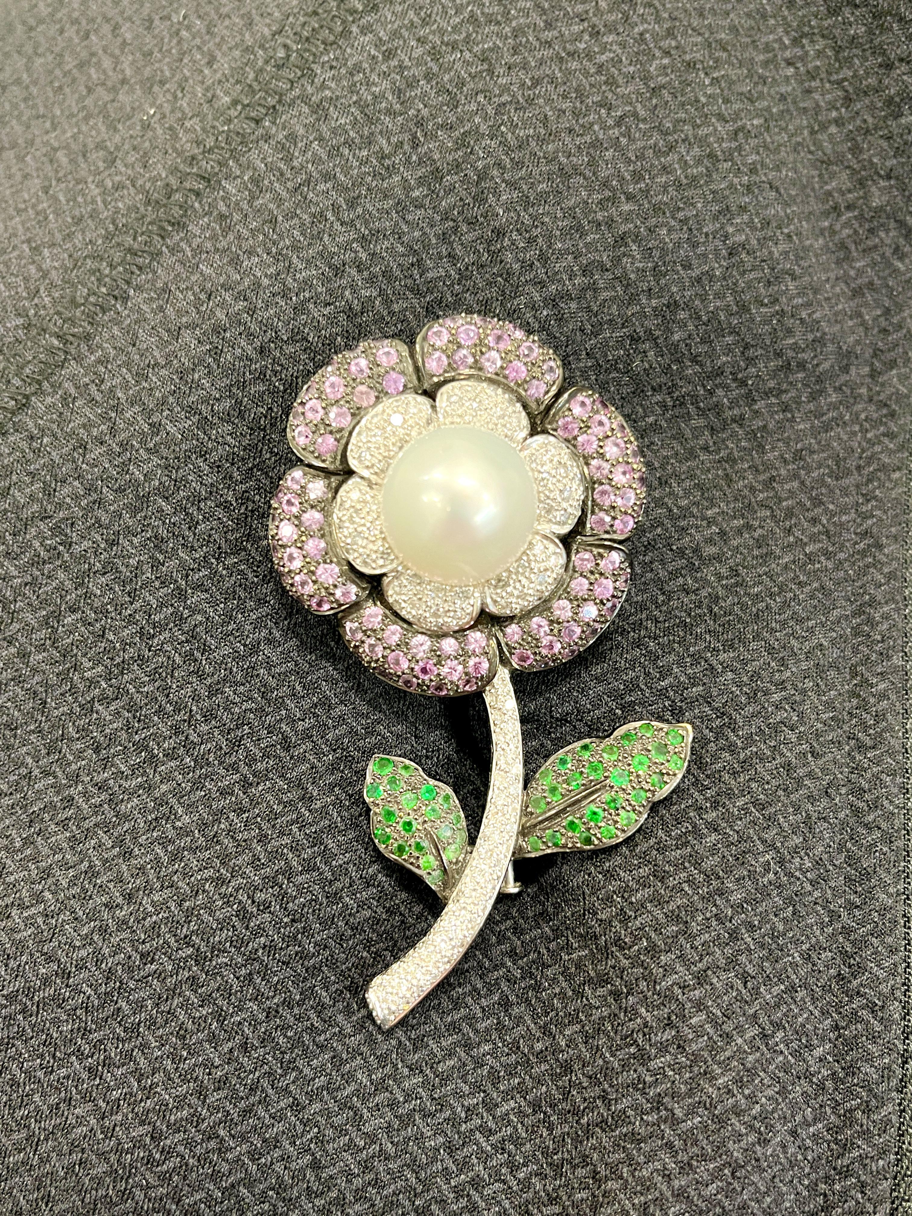 This gorgeous brooch is a definite conversation piece. The brooch features a pearl in the center of the stone, with tourmaline and tsavorite around the petals. The diamonds showcased around the pearl show a color of G/H and VS2/SI1 in clarity. A