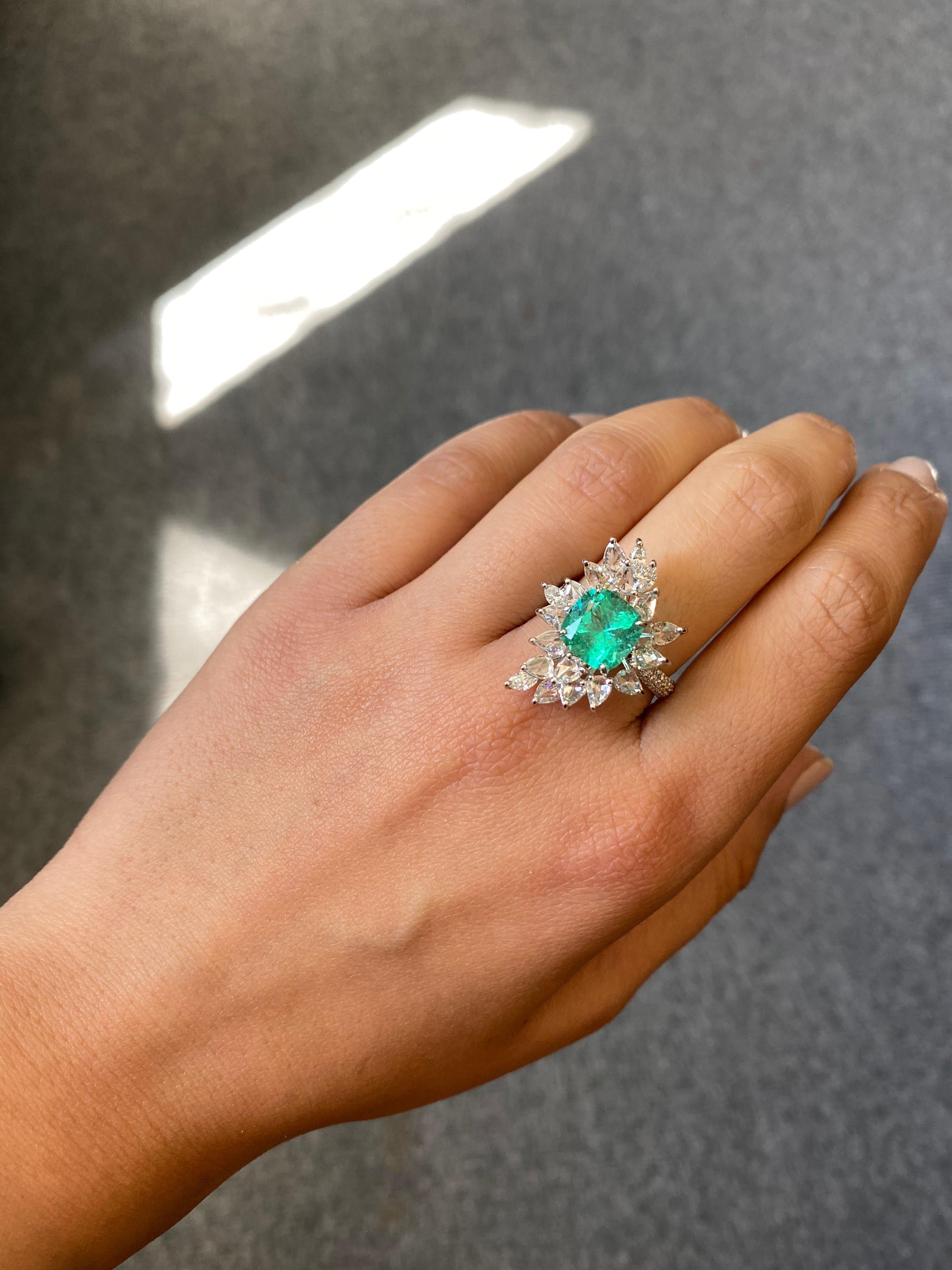 A unique cushion-shaped Colombian Emerald ring, adorned with rose-cut and full-cut marquise and pear shape diamonds all set in 18K white gold. The centre stone has a great lustre, and is completely trasnparent with very few eye-visible inclusions.