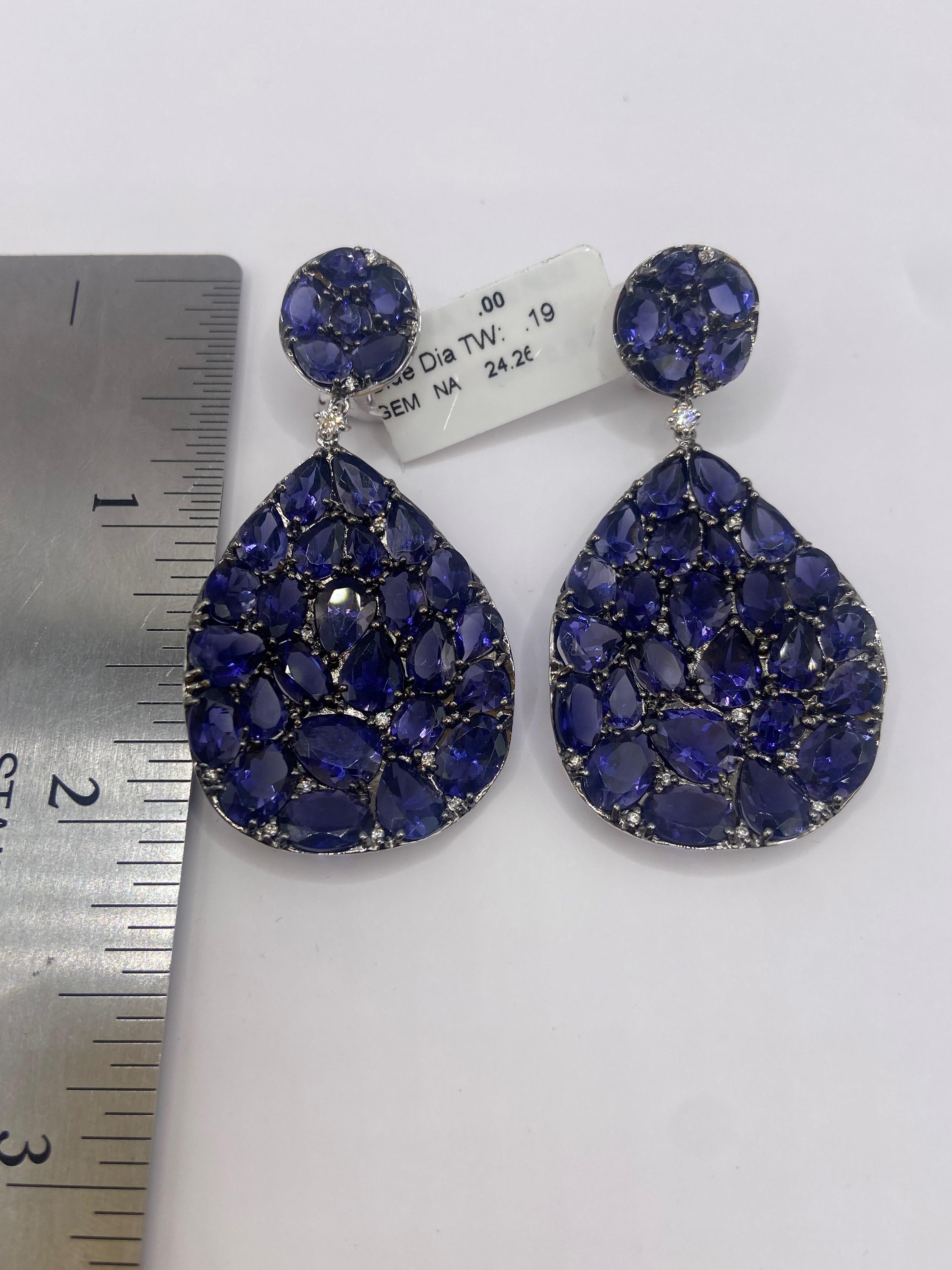 • 18KT White Gold
• 24.45 Carats

• Number of Round Diamonds: 24
• Carat Weight: .19ctw
• Color: F
• Clarity SI1

• Number of Rose Cut Blue Iolite: 62
• Carat Weight: 24.26ctw

This pair of earrings is made with 62 rose cut blue iolite stones,