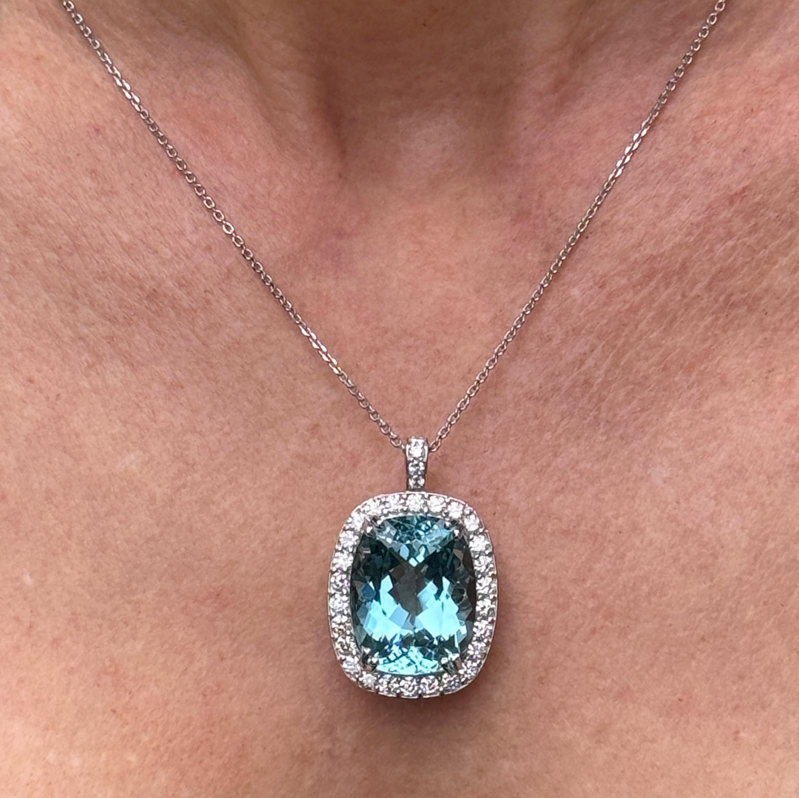 Stunning aquamarine and diamond pendant handcrafted in 18 karat white gold. The cushion cut blue aquamarine gemstone weighs 24.75 carat and has been certified by the GIA. The aquamarine is surrounded by 31 round brilliant cut diamonds weighing