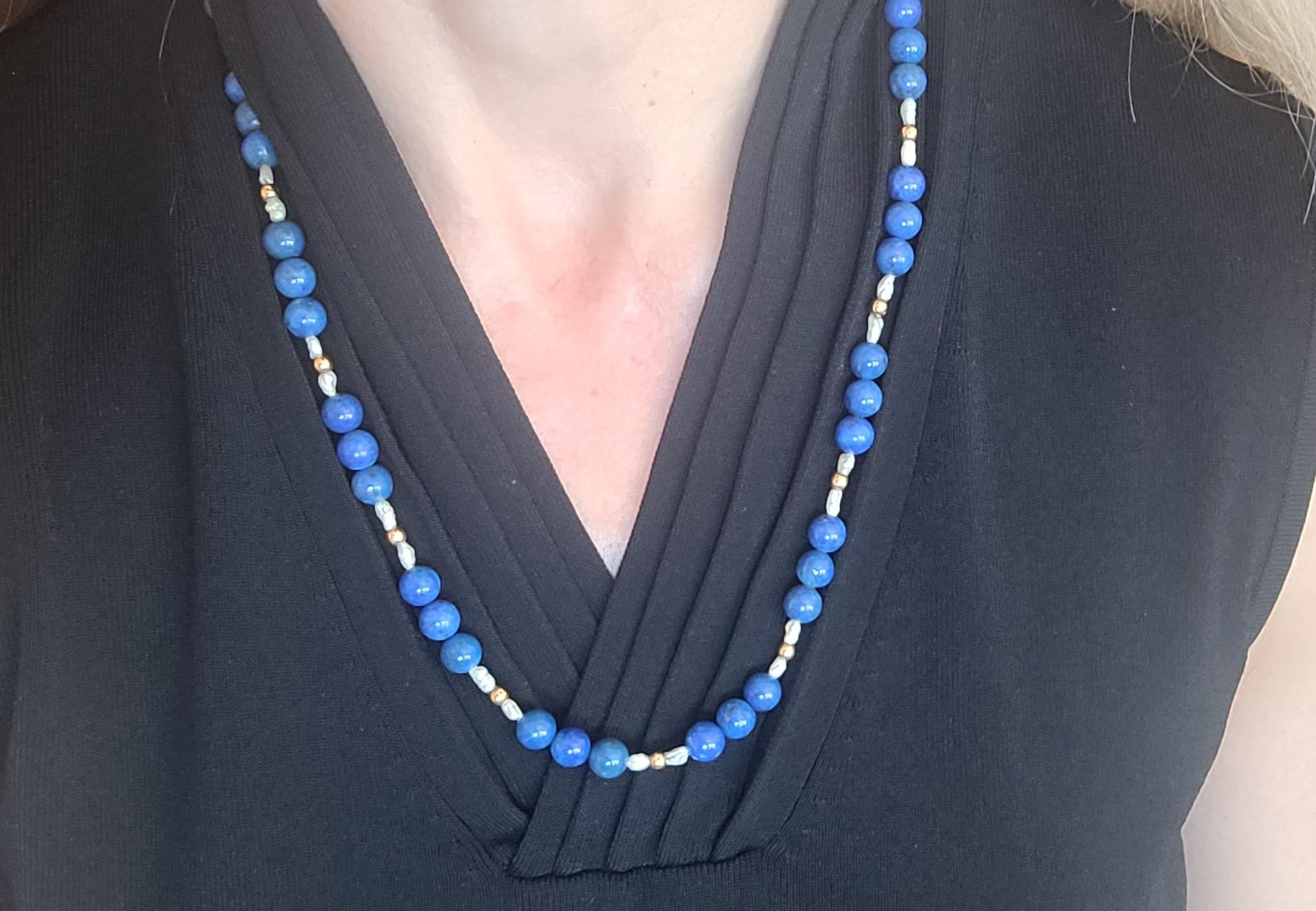 24.5-inch length necklace with  8.3mm Lapis Beads, 21 gold Beads, and 30 white freshwater Pearls; secured with a 14kt yellow gold barrel clasp. Lapis Beads are highly prized for their deep, vibrant blue color, often speckled with golden pyrite