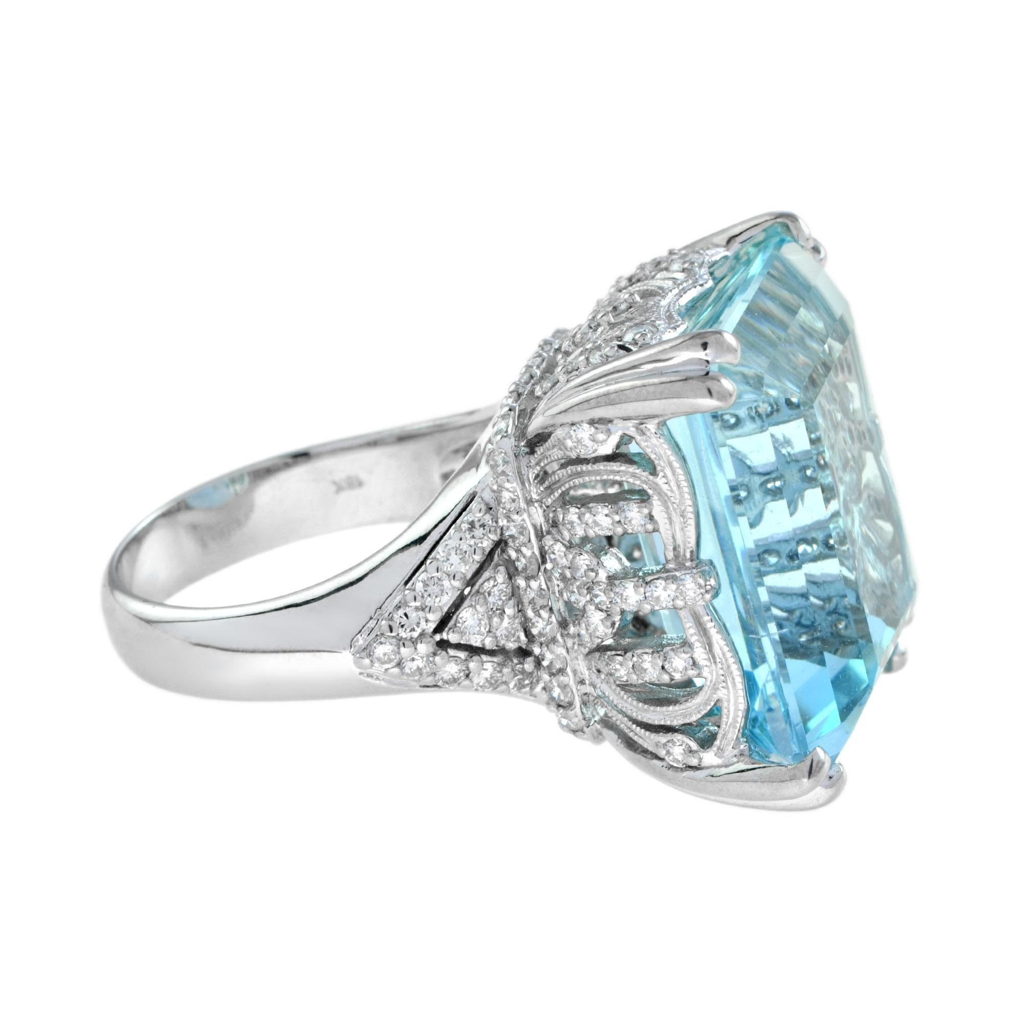 The 24.55 carats emerald cut airy sky blue hue aquamarine shows off its beautiful clarity while brilliant diamonds flank the sides and stud the split shank white gold band. The chunky gold prongs emphasize a cut cornered look for even more geometric