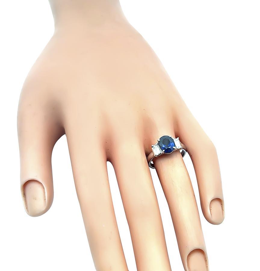 Se trata de un impresionante anillo de compromiso de platino. El anillo está centrado con un precioso zafiro de talla ovalada que pesa aproximadamente 2.45 ct. El zafiro está realzado por brillantes diamantes talla baguette de aproximadamente 0.45